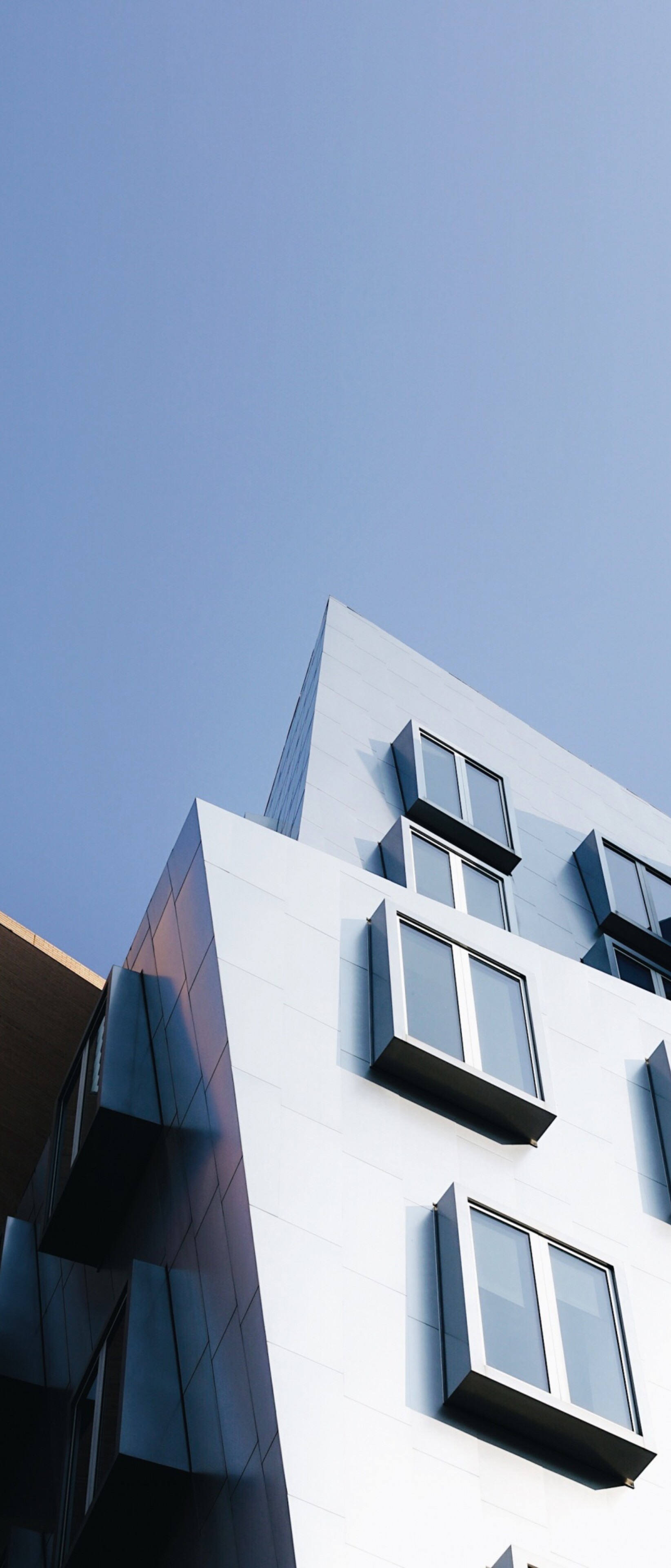 A wide shot of a modern building complex with contemporary architecture and a clear blue sky.