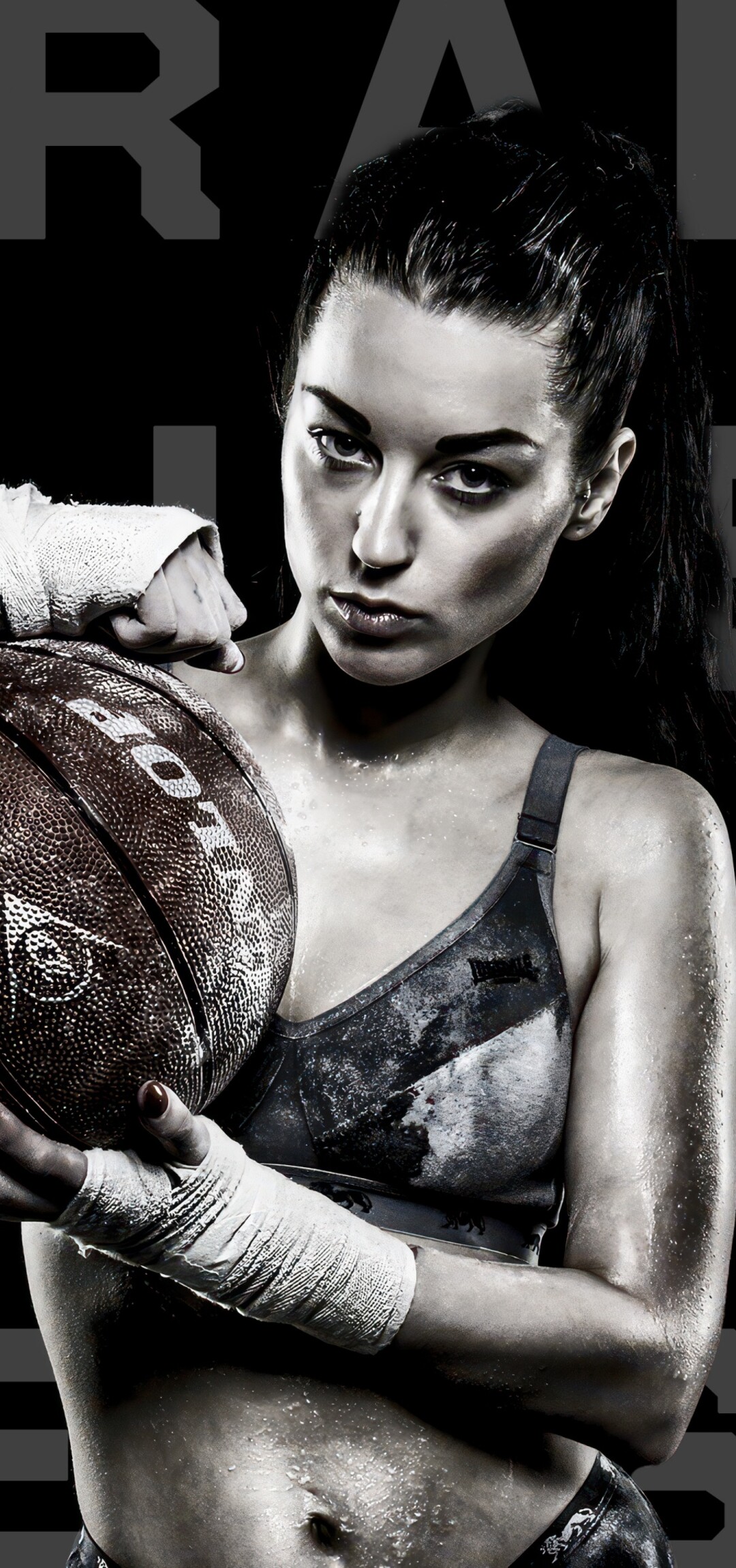 A powerful black and white close-up of an intense female basketball player looking determined against a dark background.