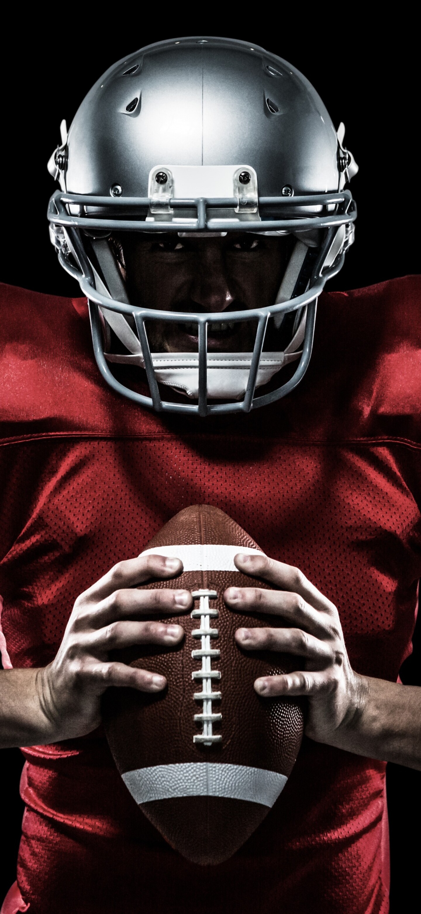 Close-up portrait of an American football player wearing a helmet and jersey against a solid black background.