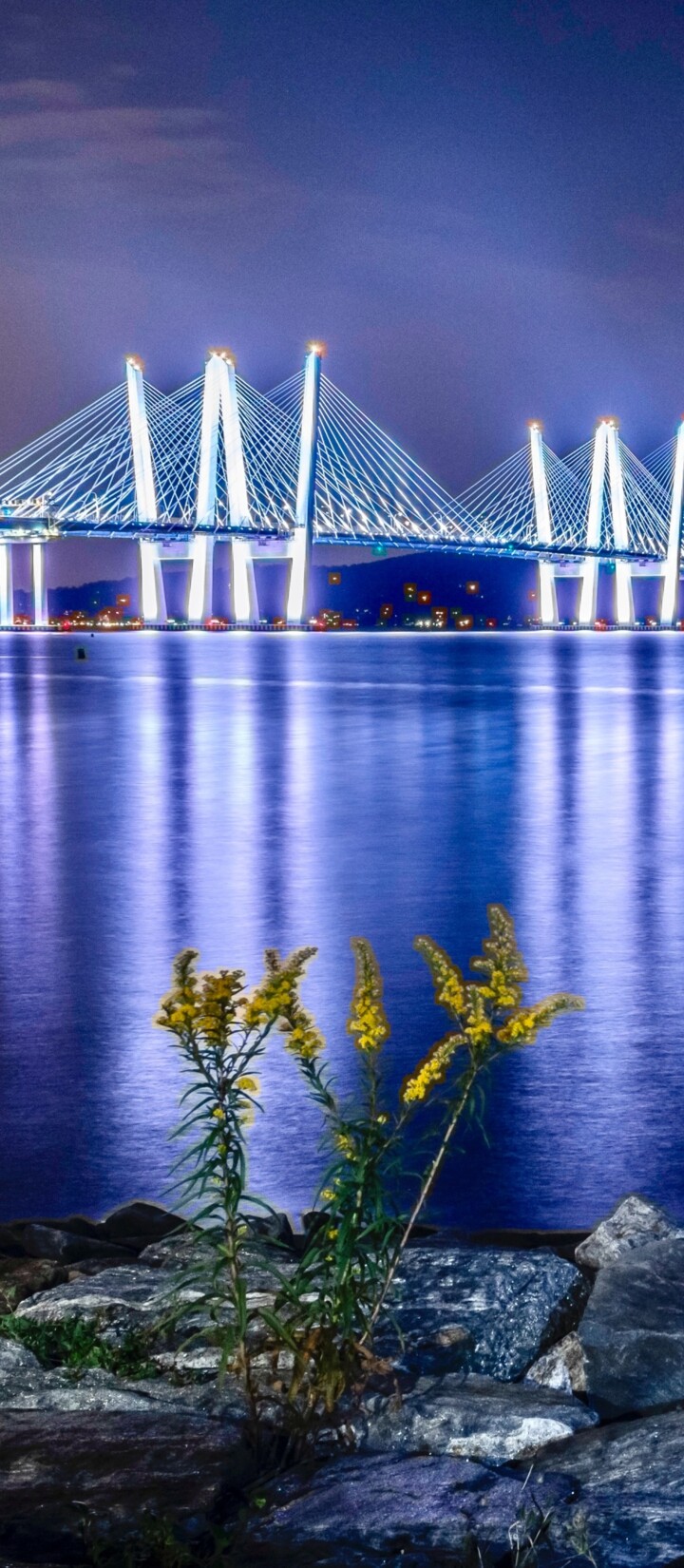 A tranquil river landscape at dusk with vibrant sunset colors reflecting on the calm water surface.