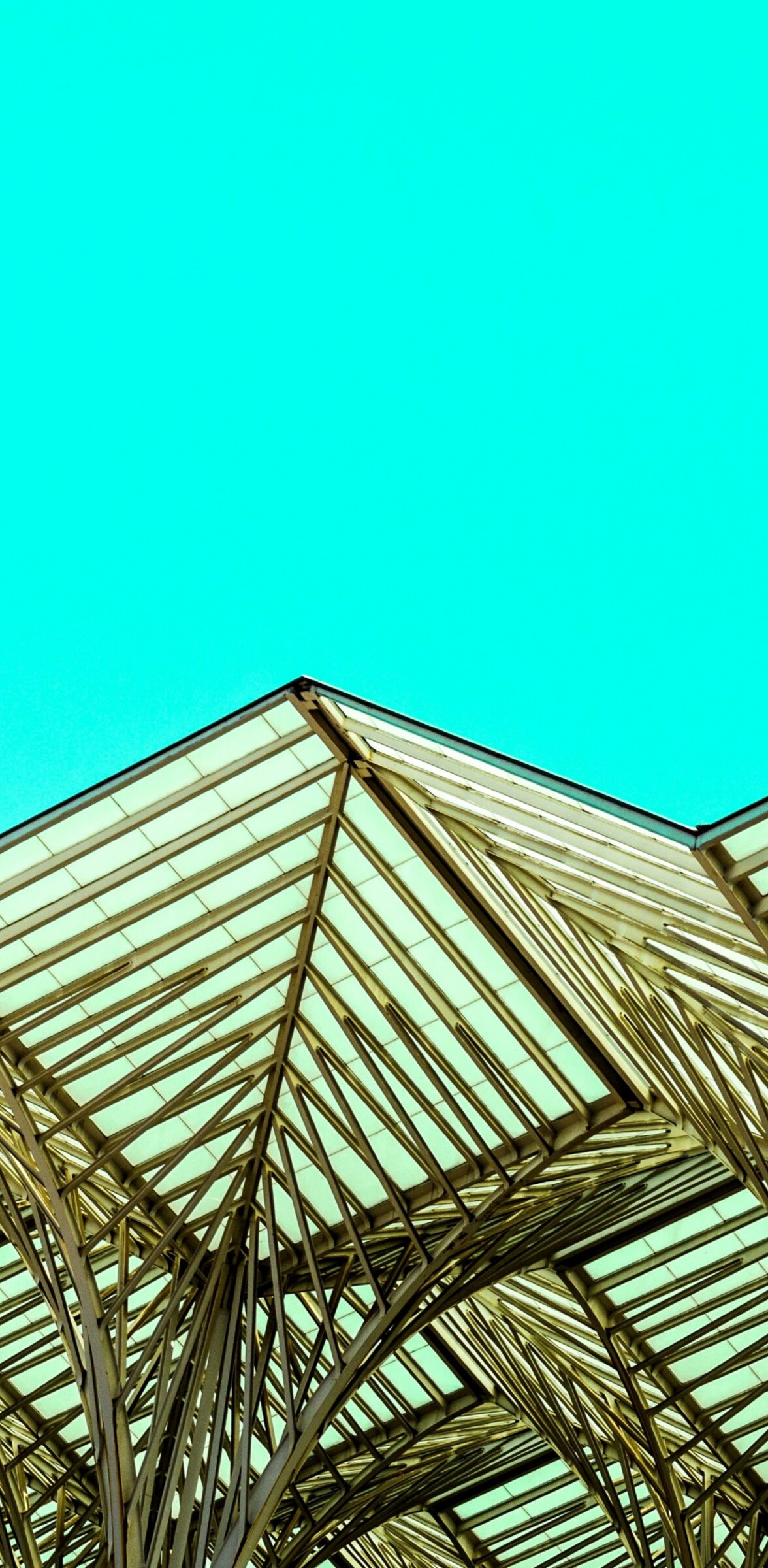 Close-up of modern metal architecture with geometric patterns and sharp edges against a bright blue sky.