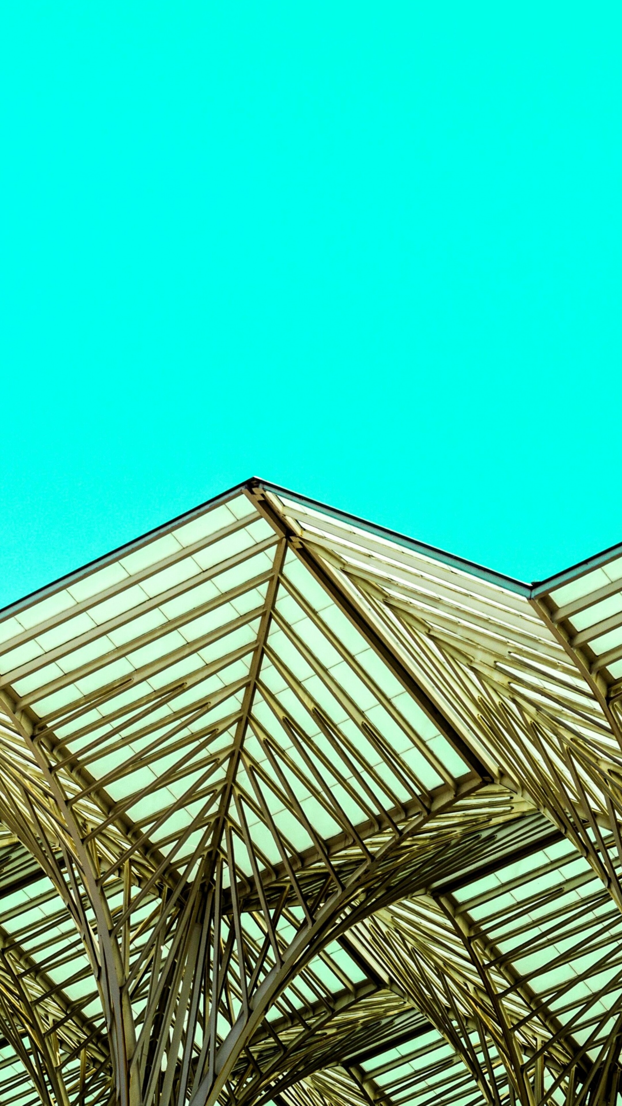 Close-up of modern metal architecture with geometric patterns and sharp edges against a bright blue sky.