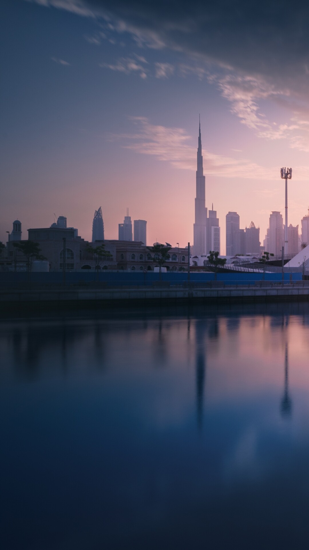 A panoramic view of the Dubai cityscape at sunset with modern skyscrapers and waterfront architecture.