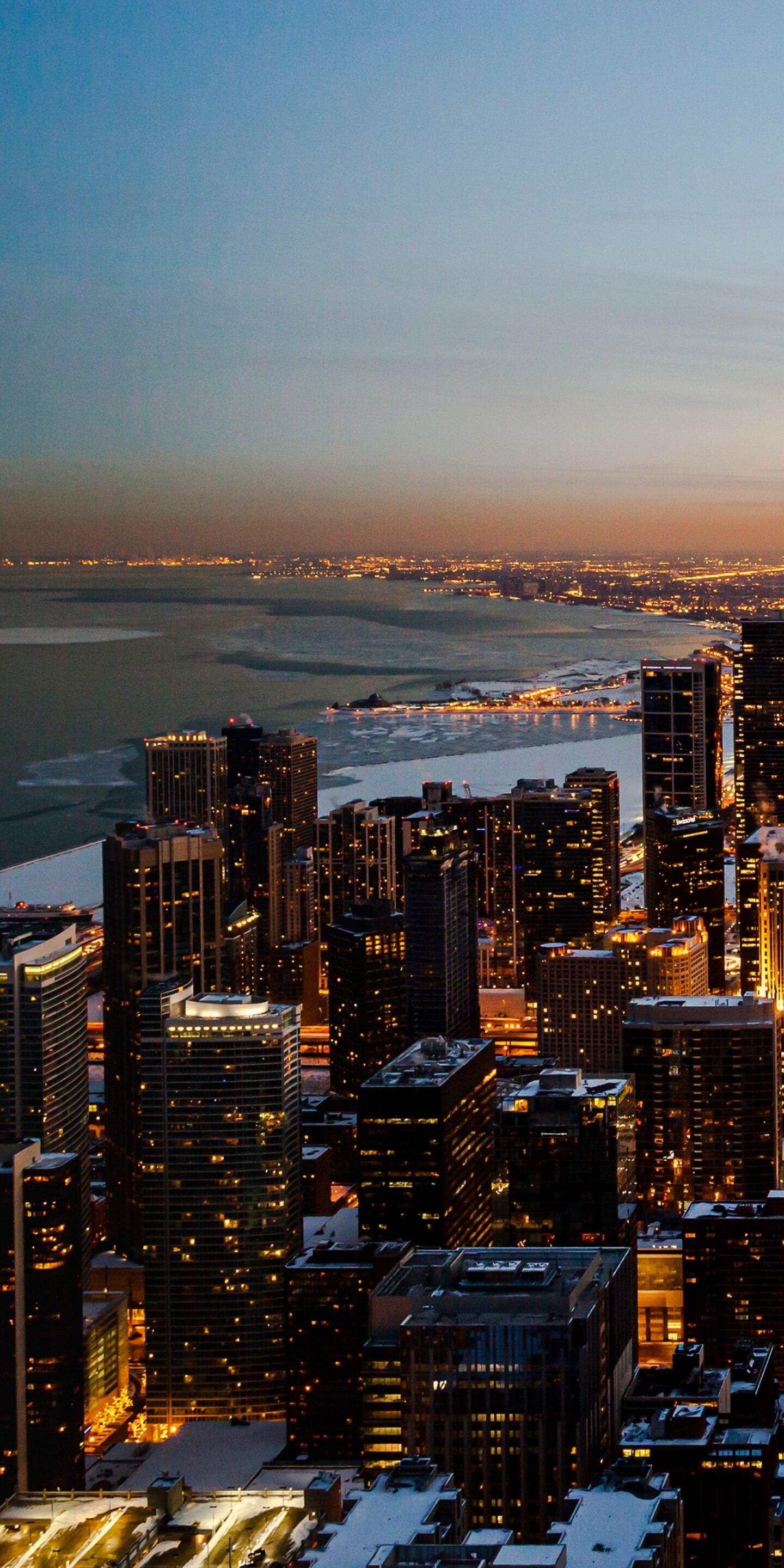 Aerial view of the Chicago downtown skyline at sunset with skyscrapers and urban cityscape under a dusk sky.