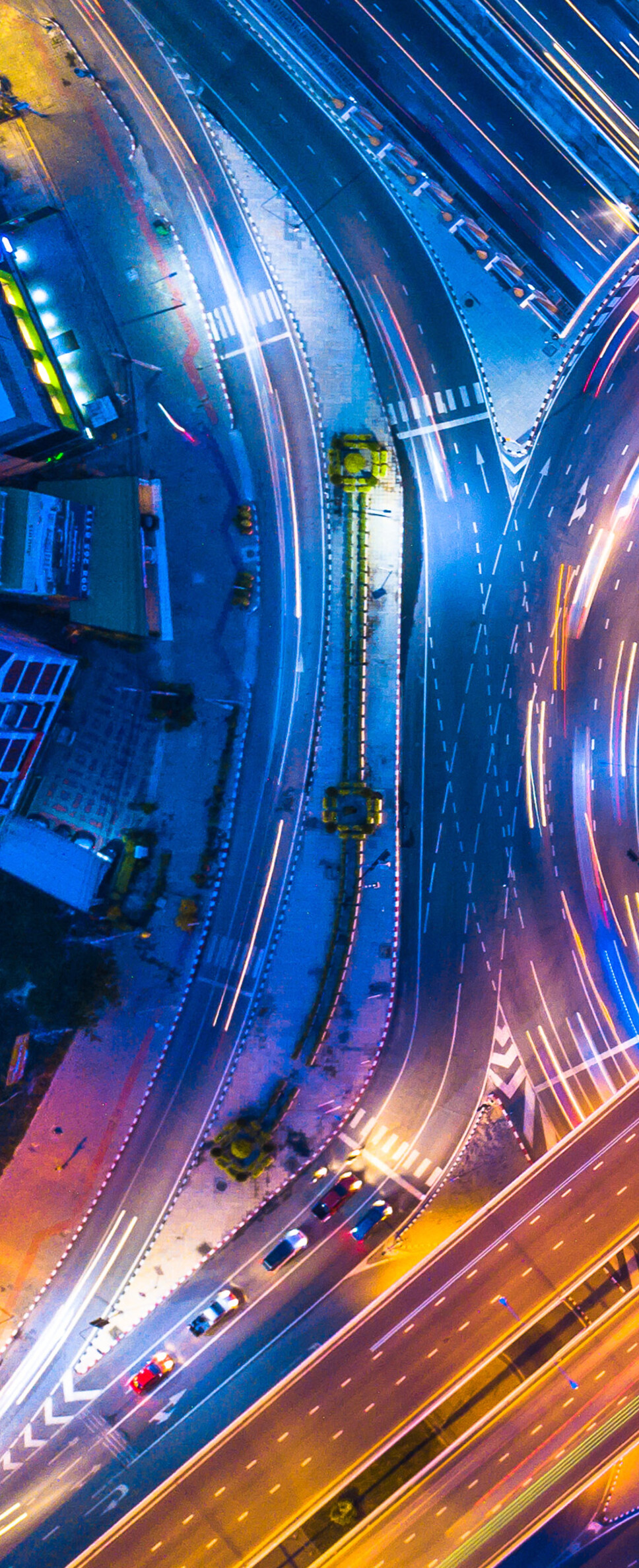 Aerial photography of a Bangkok city intersection at night with colorful long exposure light trails.