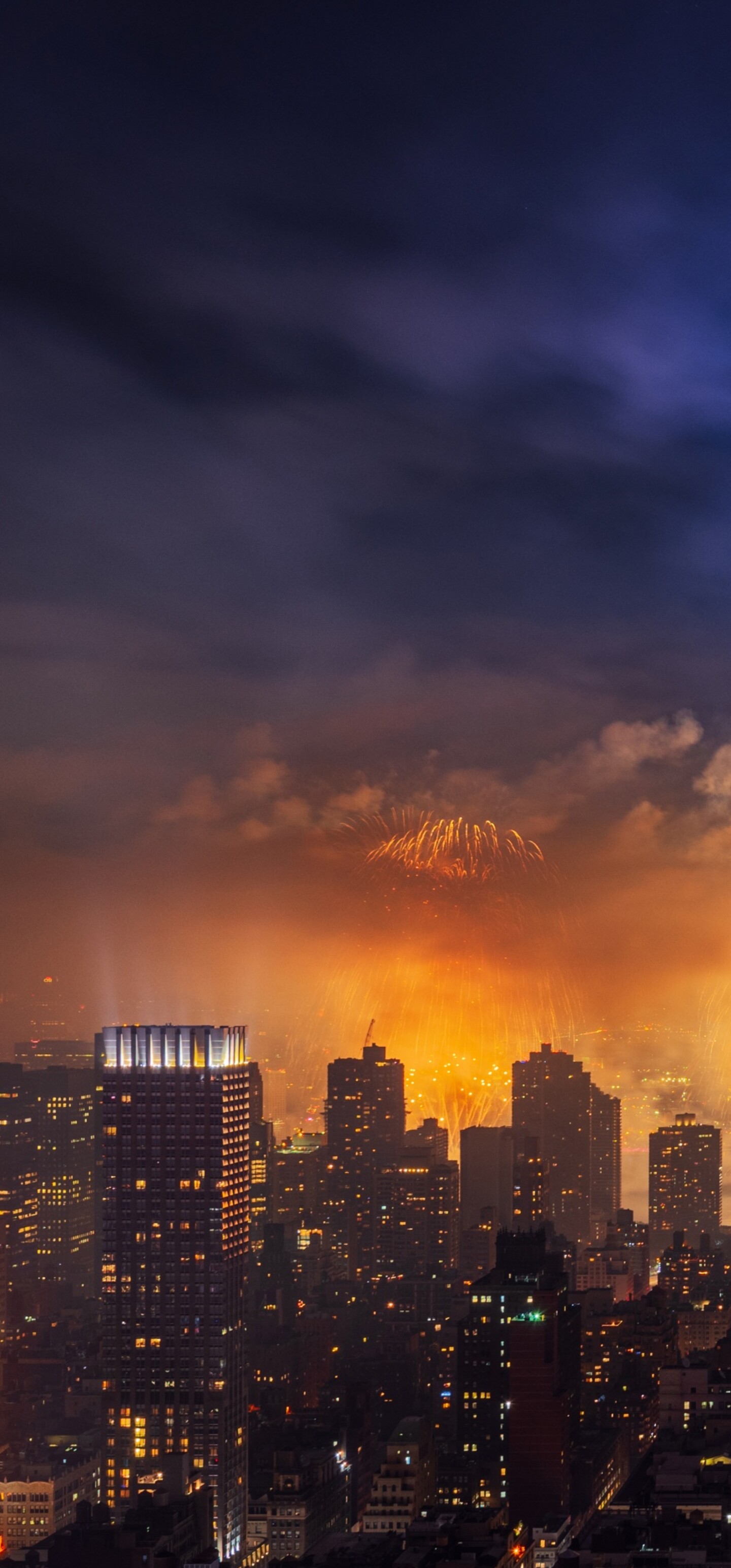 Night view of the Empire State Building with colorful fireworks exploding over the New York City skyline.