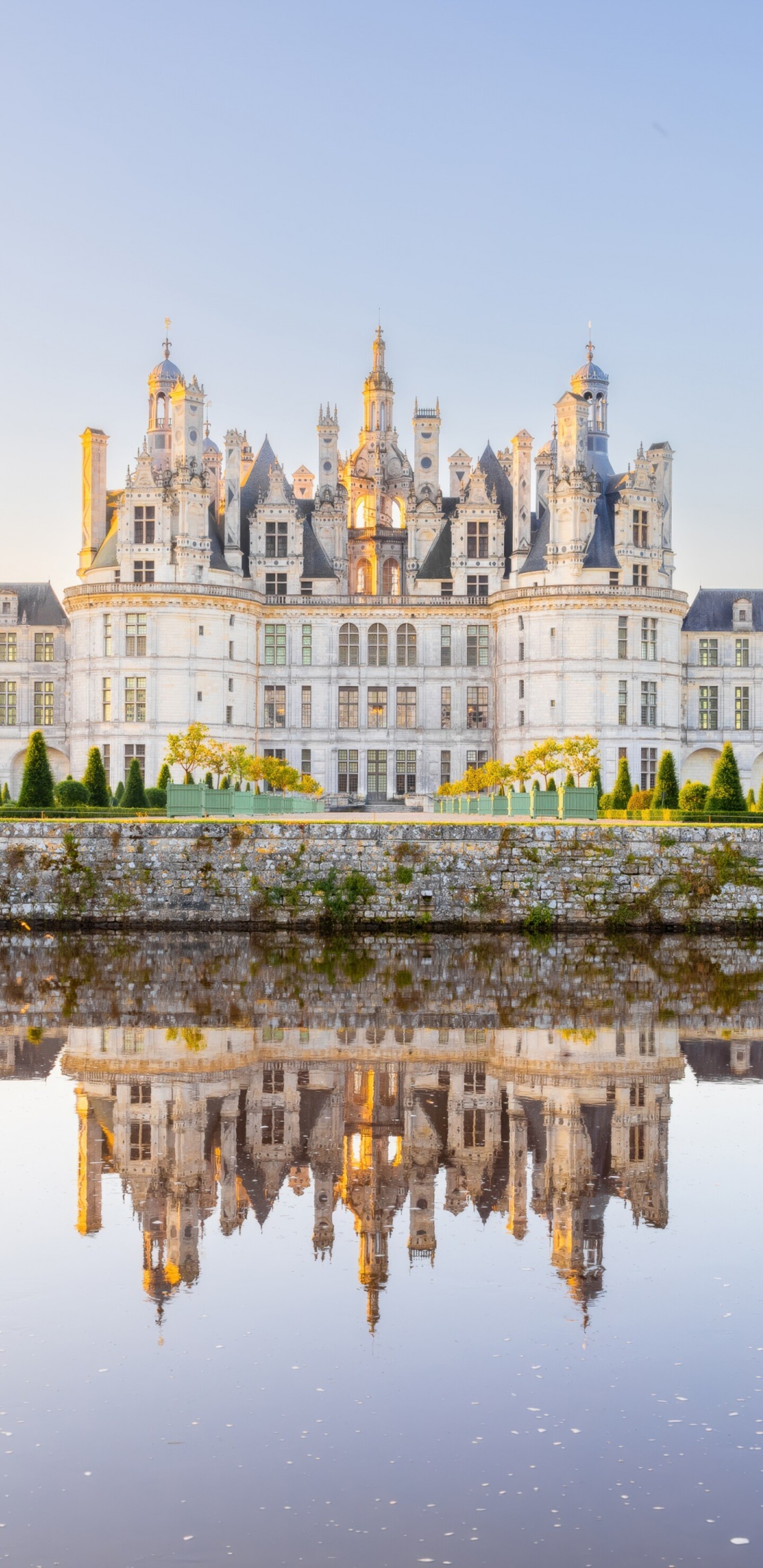Scenic view of ancient French architecture reflecting in clear water during the day.