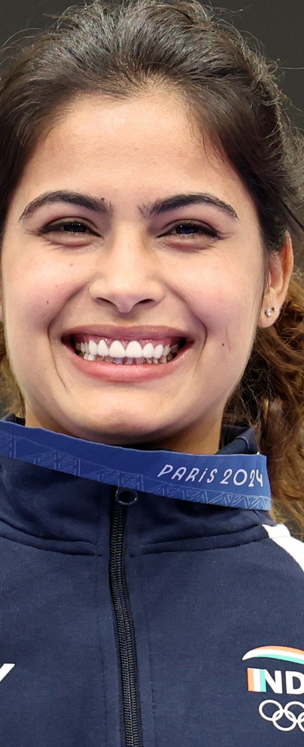 A close-up portrait of Indian Olympic shooter Manu Bhaker with a focused gaze.