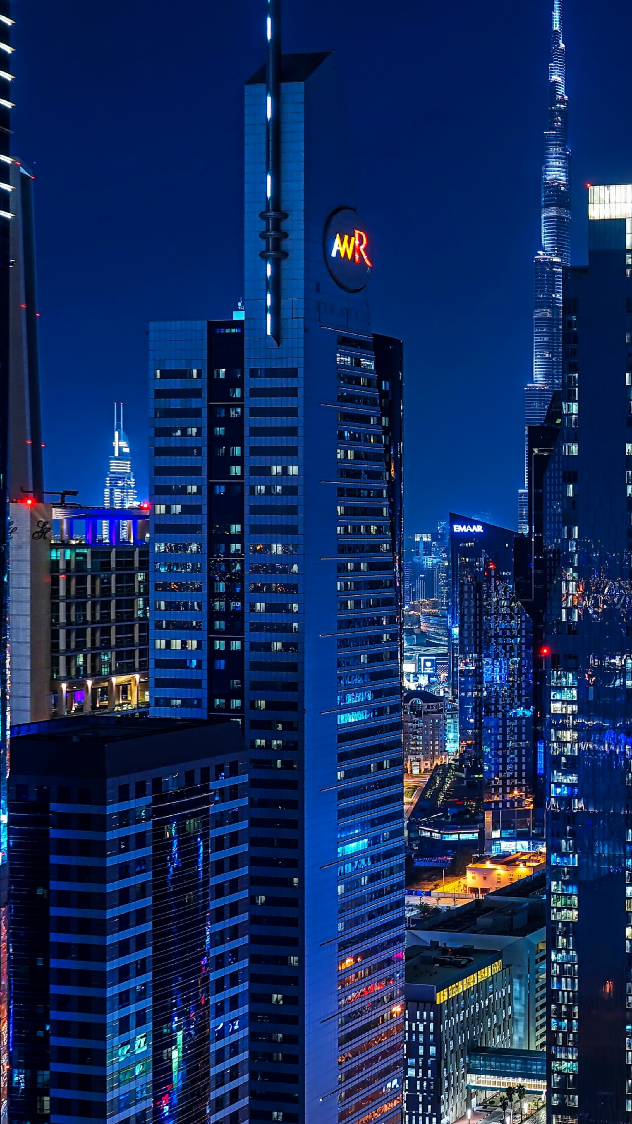 A panoramic night view of the Dubai skyline with illuminated skyscrapers and bright city lights on Sheikh Zayed Road.