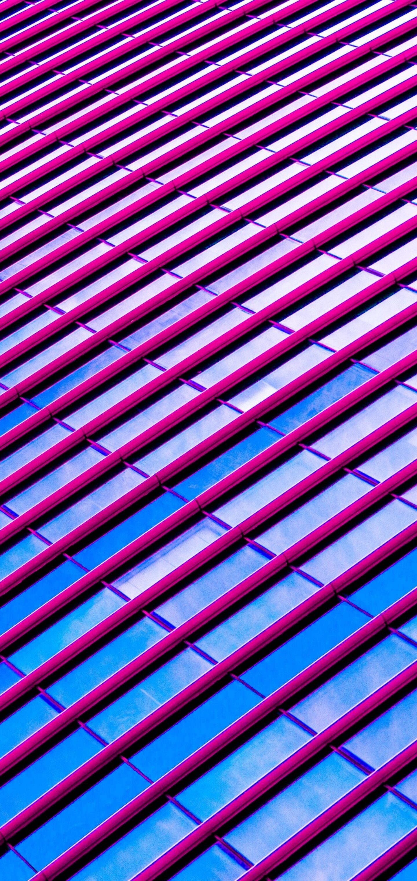 Symmetrical pink modern building with geometric patterns and large glass windows.