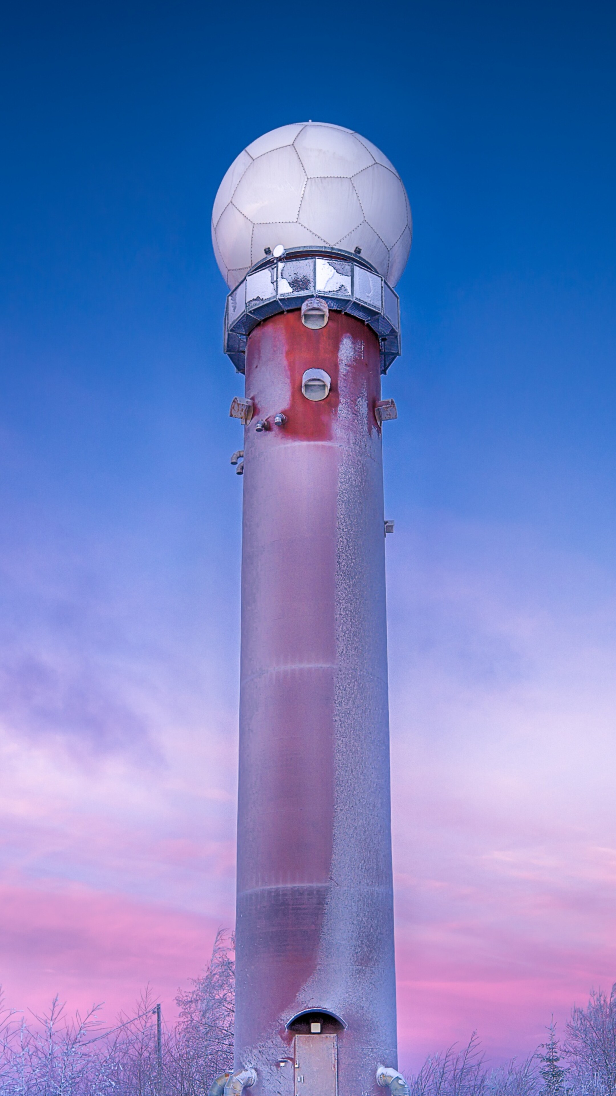 A snow-covered winter landscape featuring a vibrant purple sunrise sky and crystalline frost.