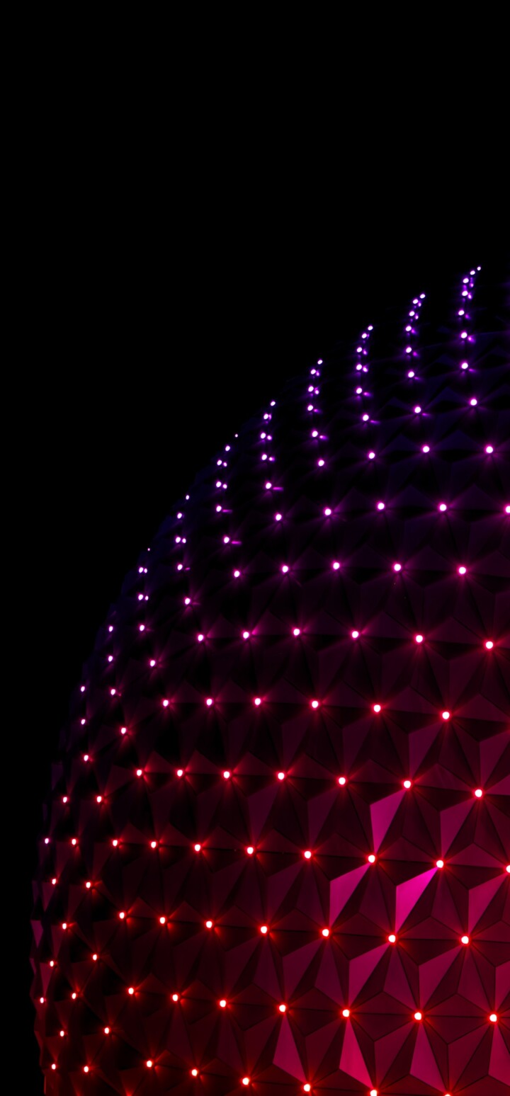 The glowing, illuminated geodesic sphere of Spaceship Earth at Epcot during the night.