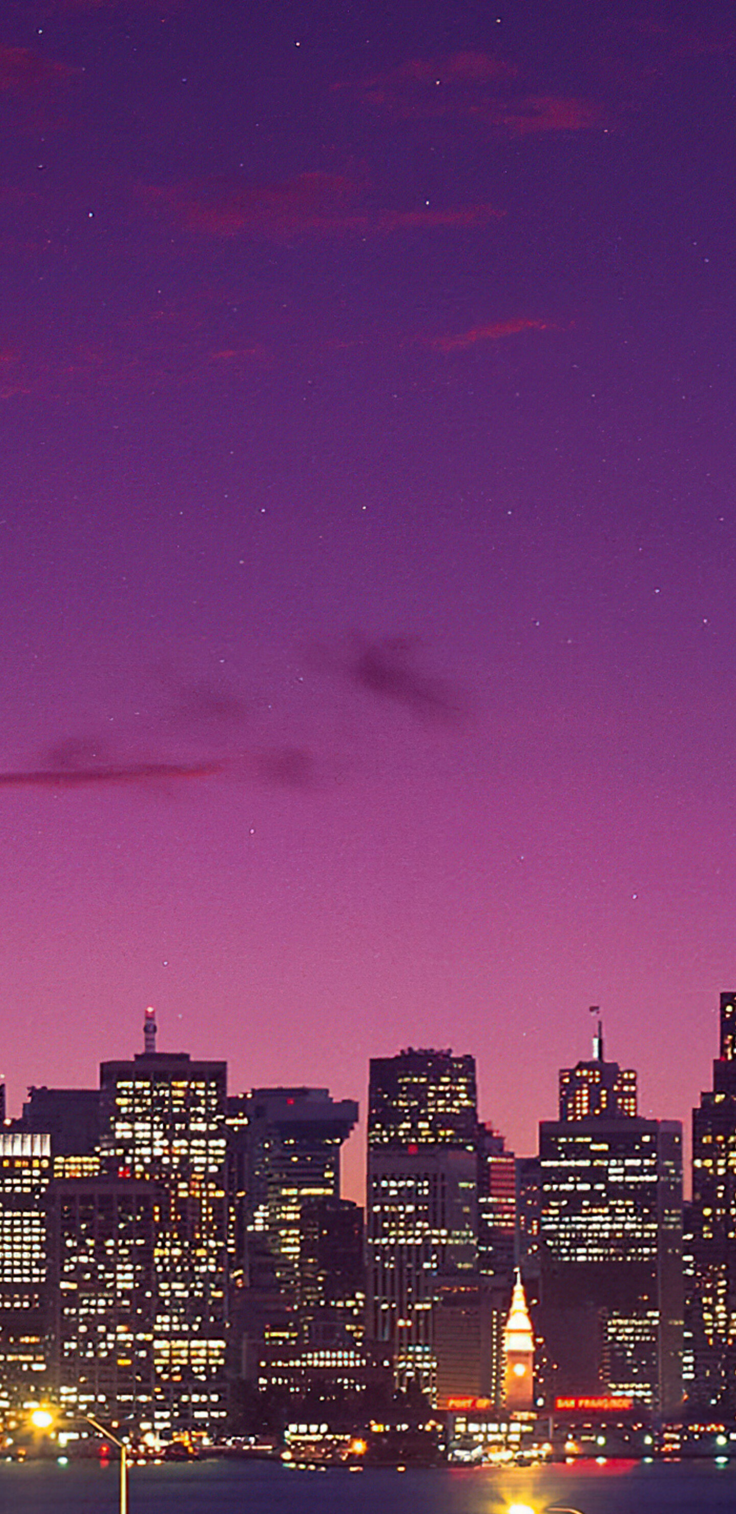Long exposure shot of the San Francisco-Oakland Bay Bridge under a purple gradient twilight sky with a crescent moon.