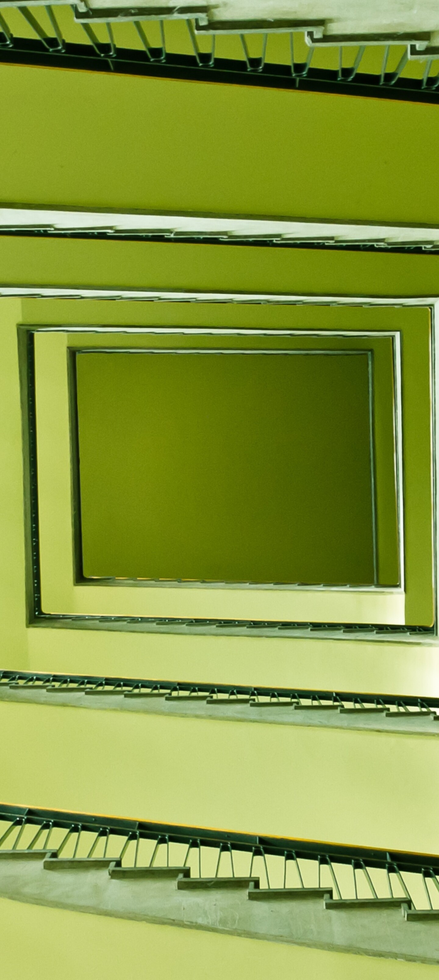 A low-angle shot looking up at a staircase with a vibrant green geometric pattern.