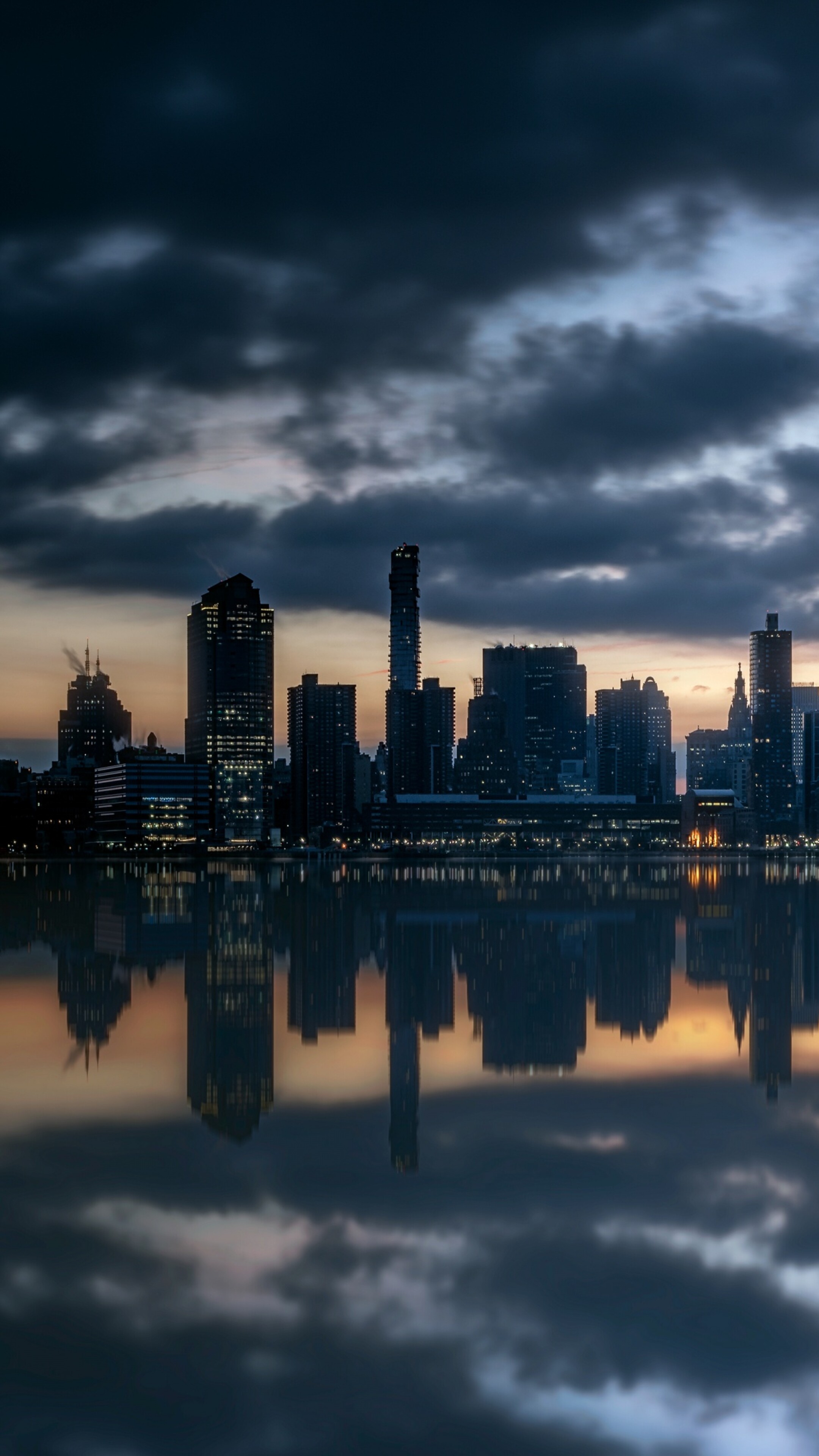 The Manhattan skyline and skyscrapers reflected in the Hudson River during a beautiful dusk in New York City.