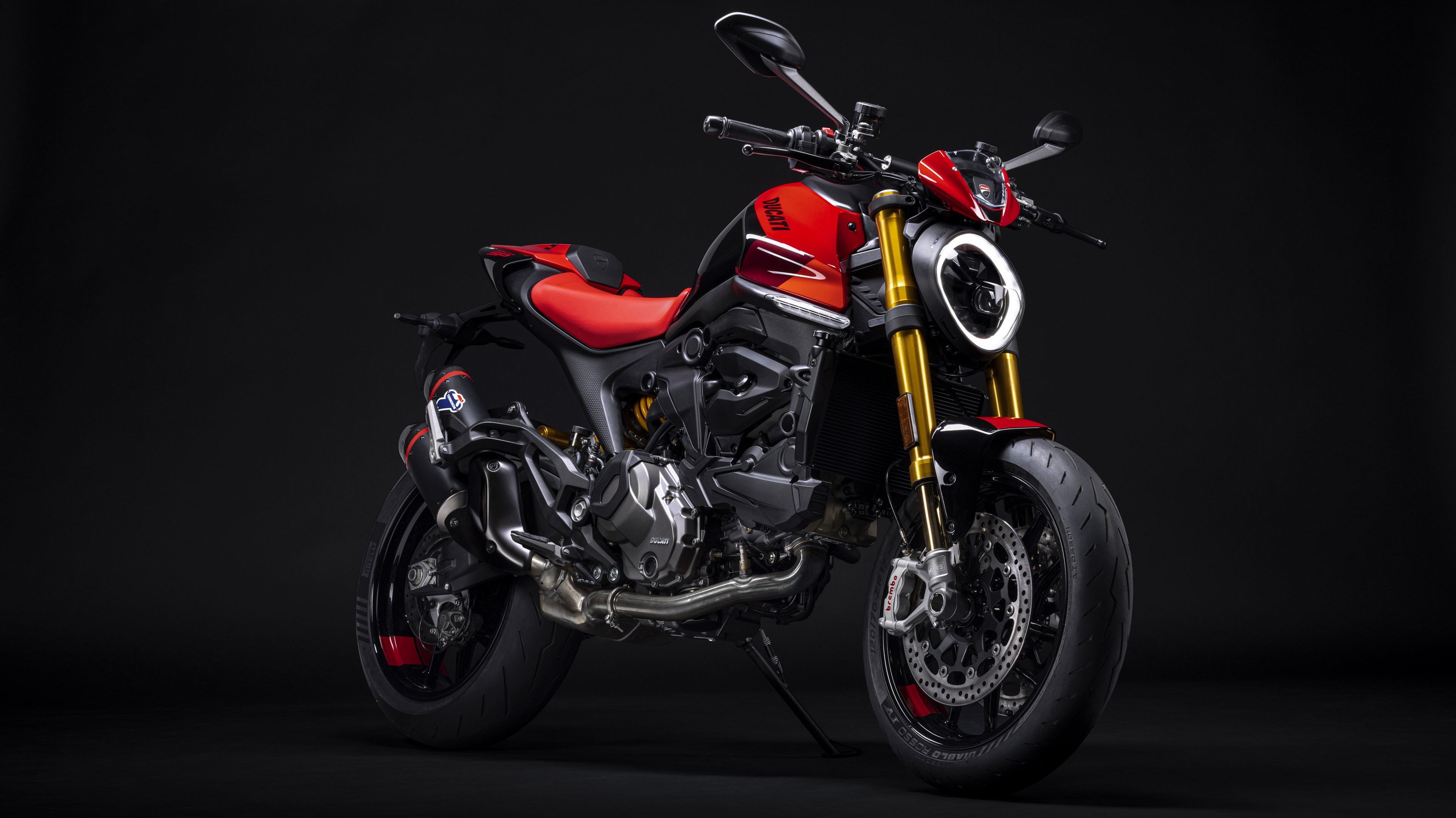 A close-up, dramatic shot of a 2023 Ducati Monster SP motorcycle against a dark, moody background.