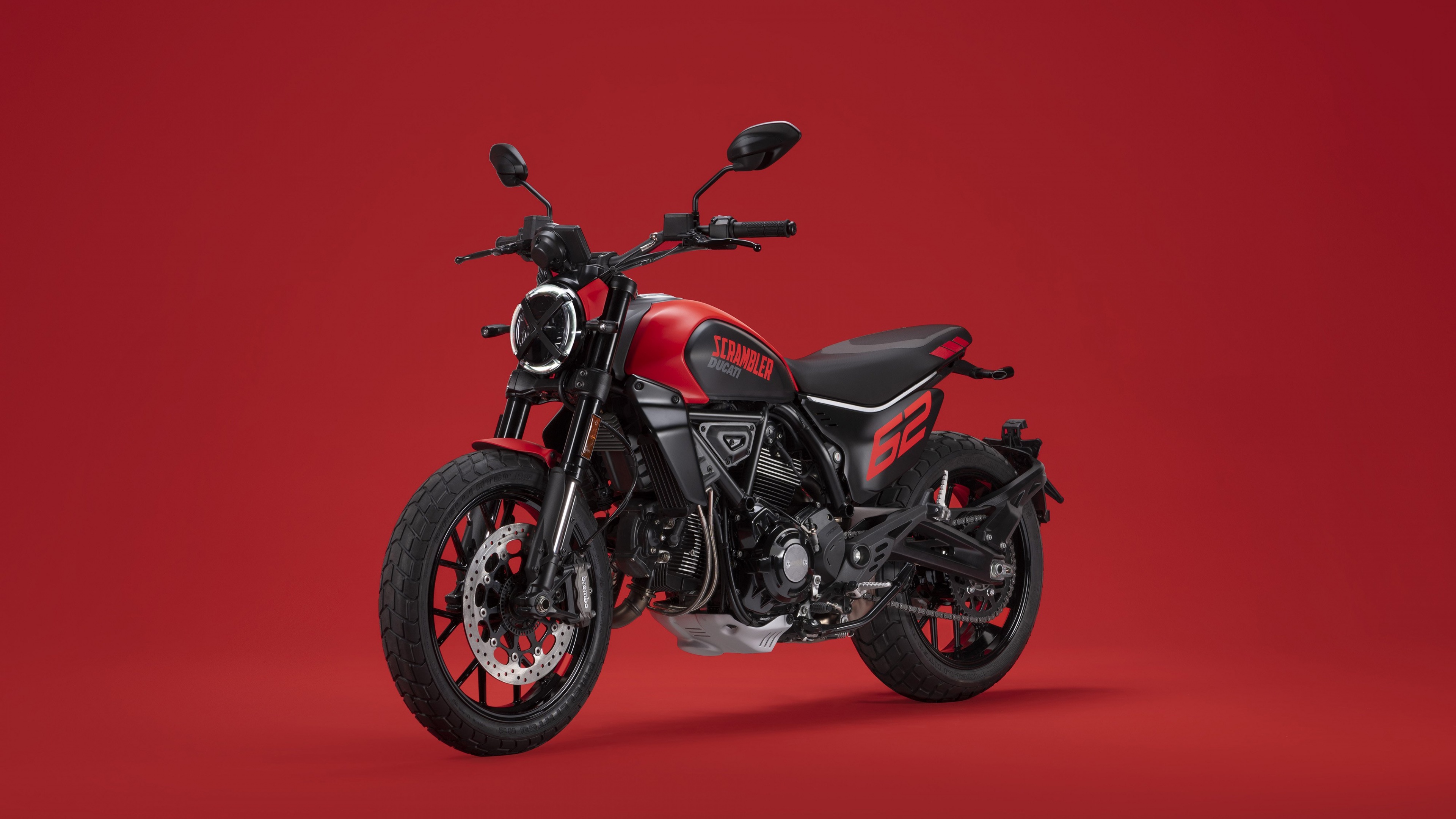 A 2023 Ducati Scrambler Full Throttle motorcycle positioned against a bright red background.