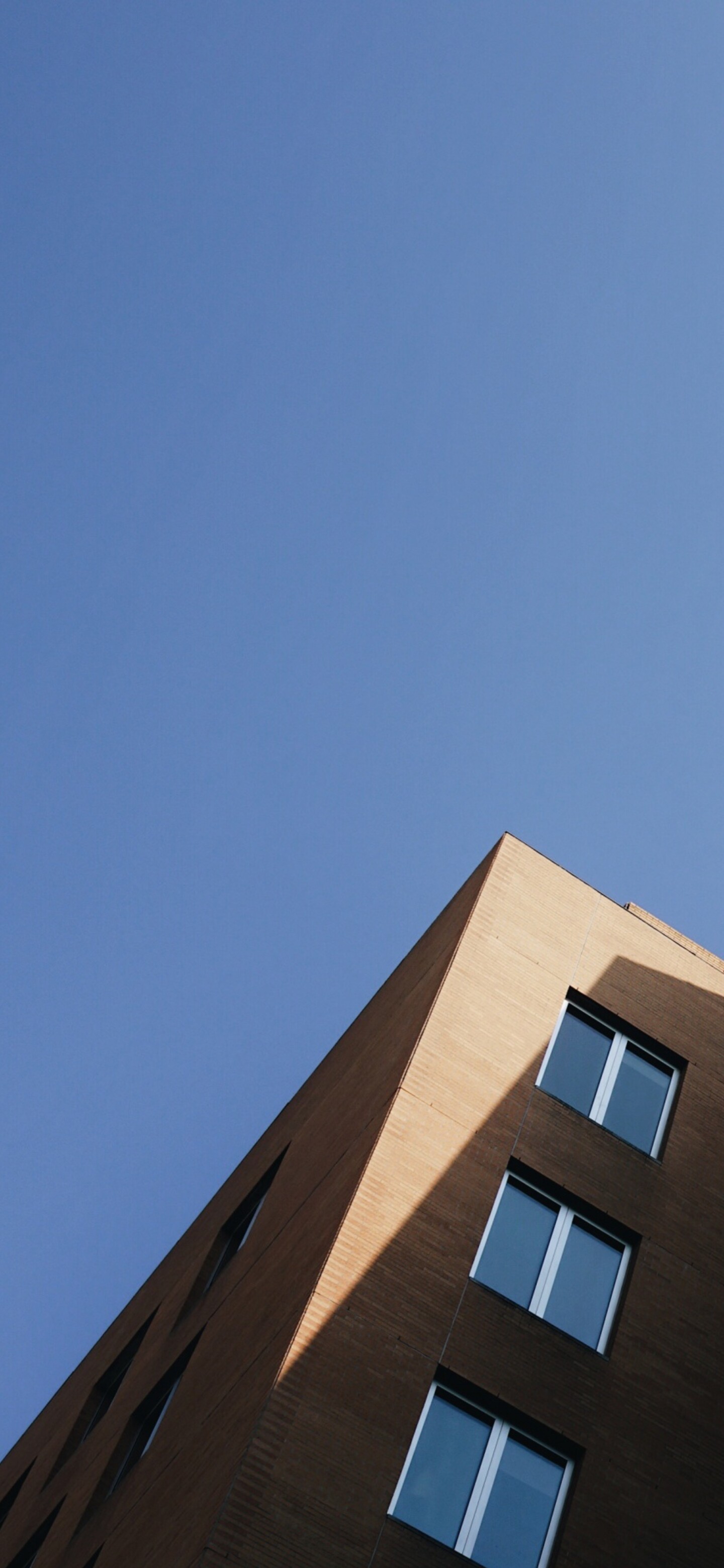 A wide-angle shot of a large, modern glass and steel building complex under a clear, bright sky.