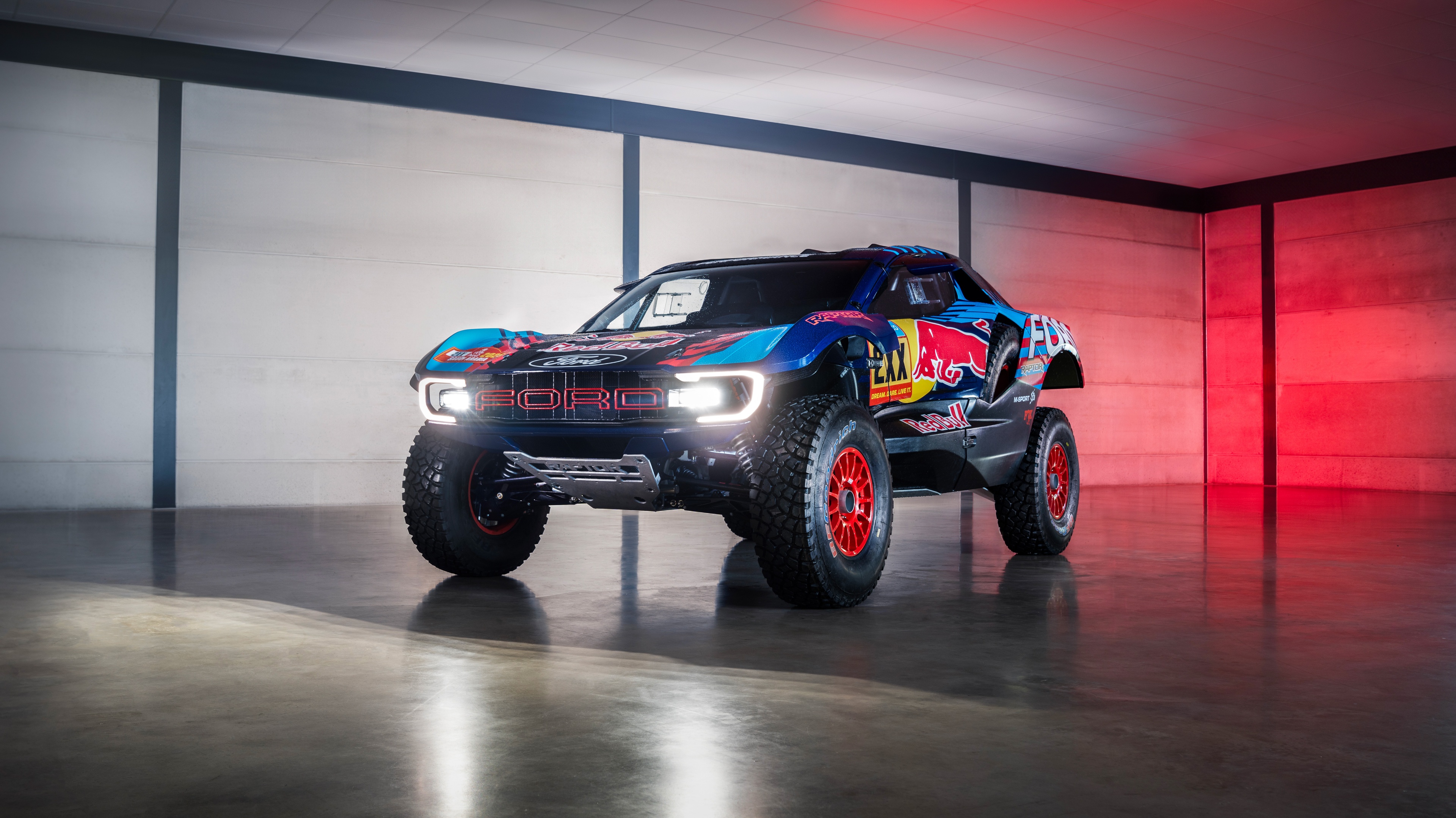 A group of high-performance rally cars and off-road trucks racing through a dusty, rugged landscape.