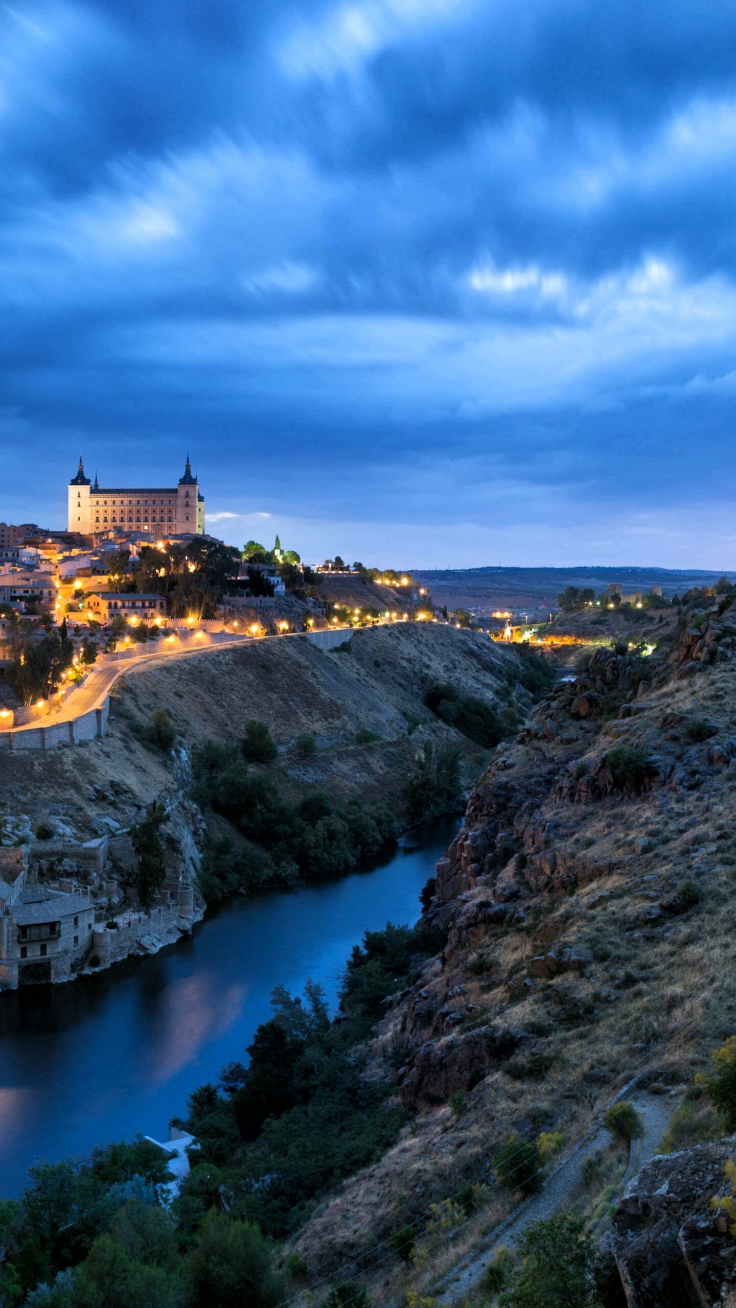 A wide panoramic view of a Spanish city at night featuring bright city lights and urban architecture.