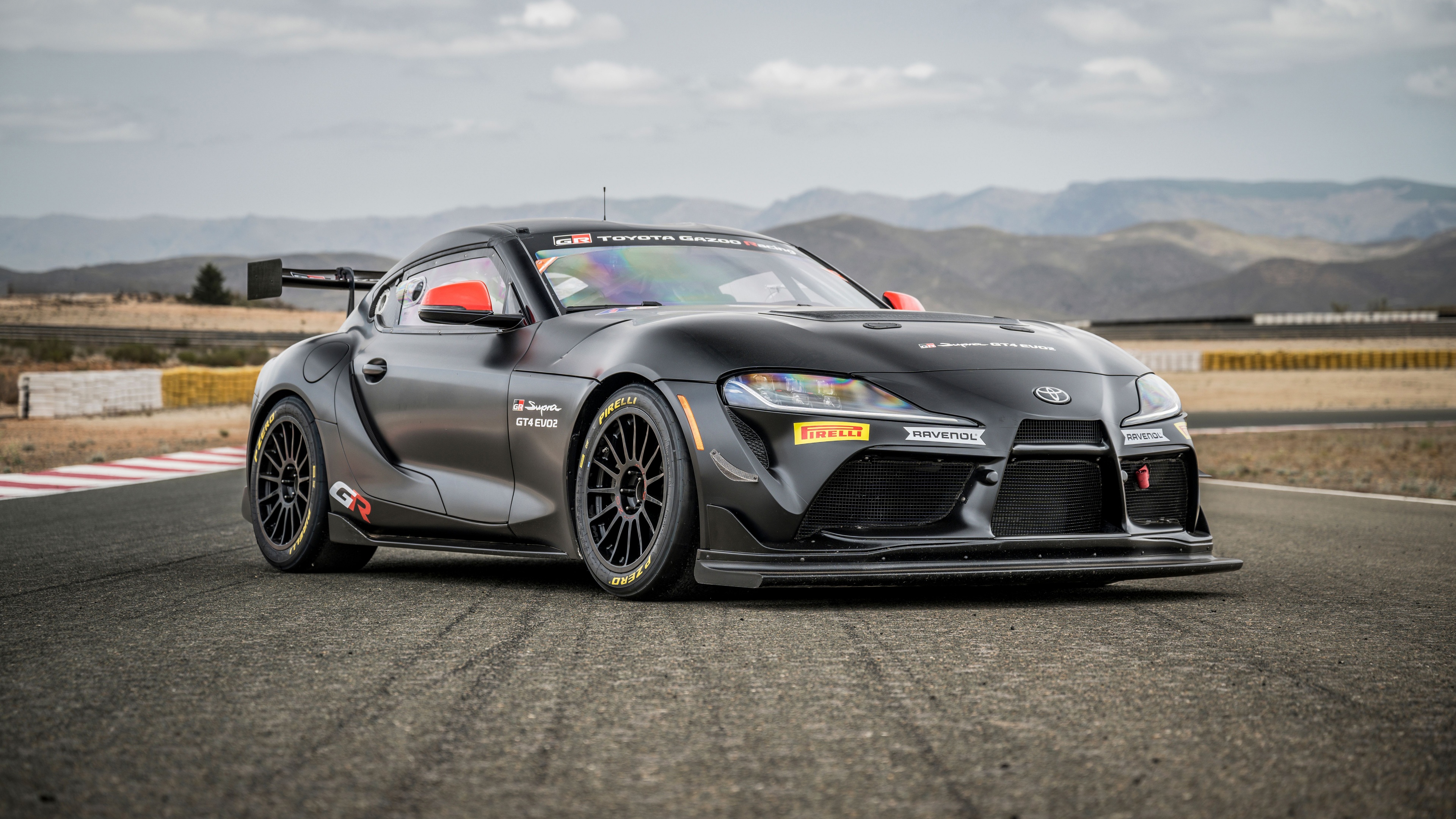 A high-resolution, detailed shot of a Toyota GR Supra GT4 racing prototype driving on a professional race track circuit.
