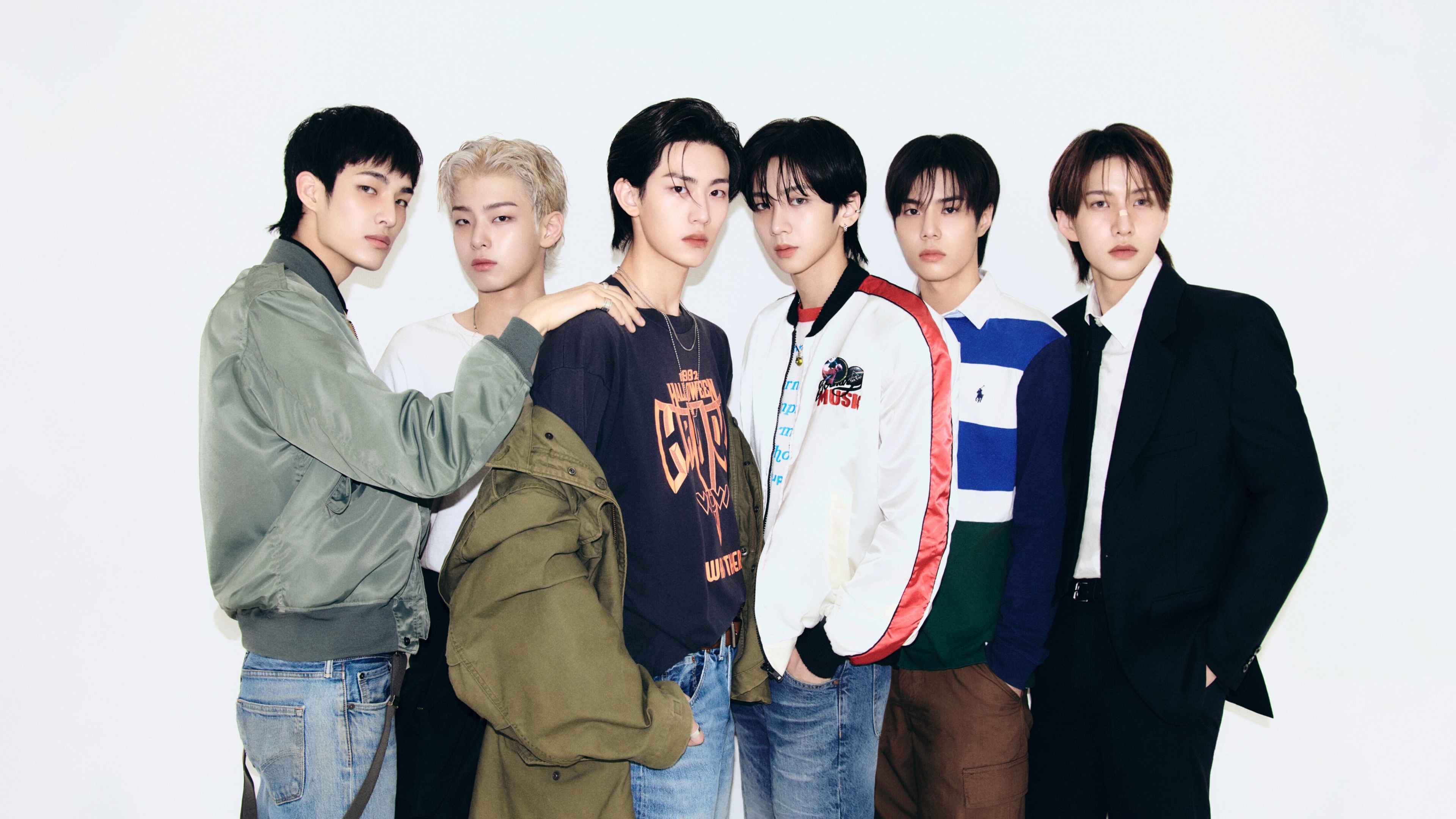 A group of stylish South Korean K-Pop male singers posing for a professional group photoshoot.