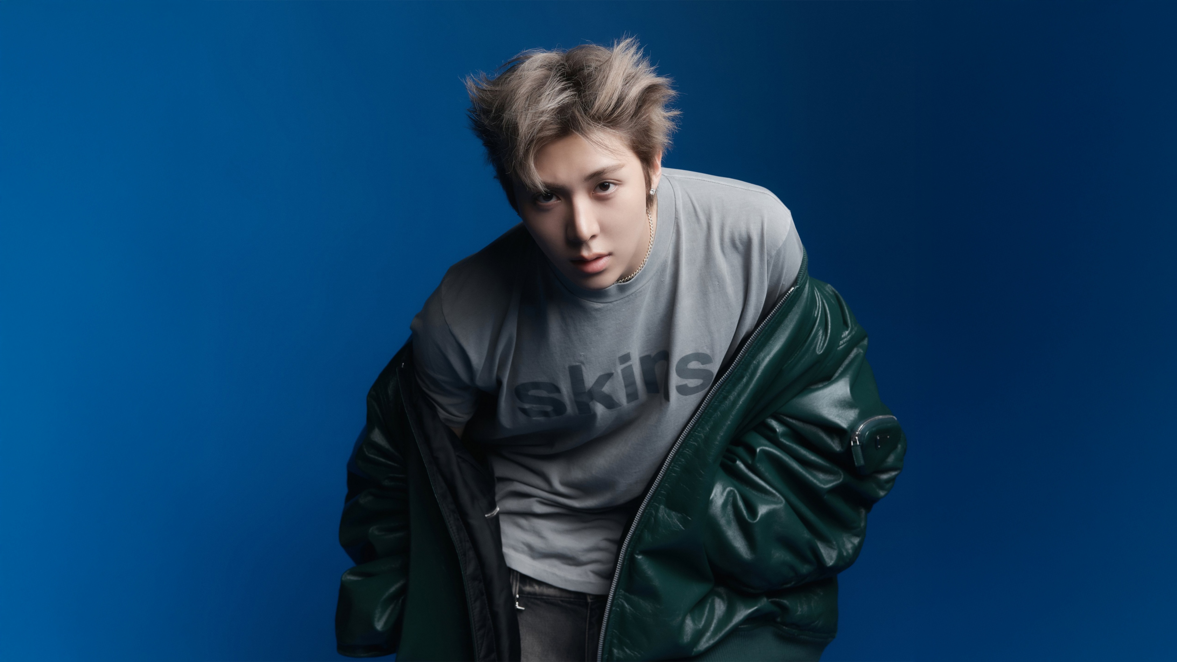 A high-definition portrait of South Korean rapper Woochan from ALLDAY PROJECT against a bold blue background.