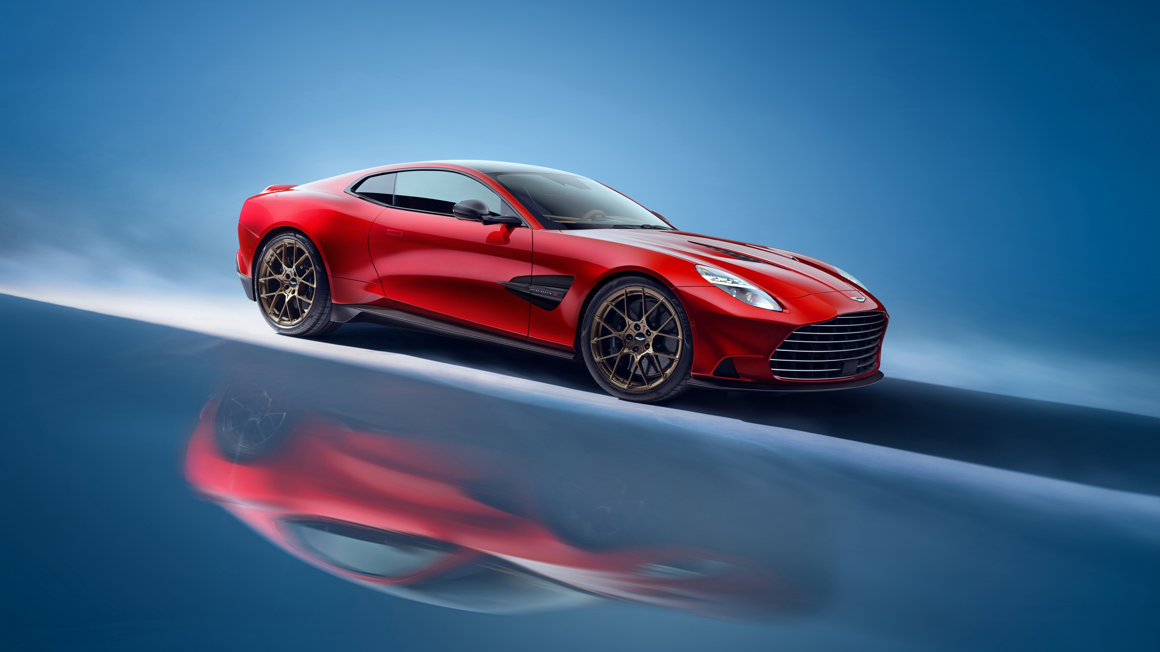 A high-detail shot of a 2024 Aston Martin Vanquish super sports car against a vibrant blue background.