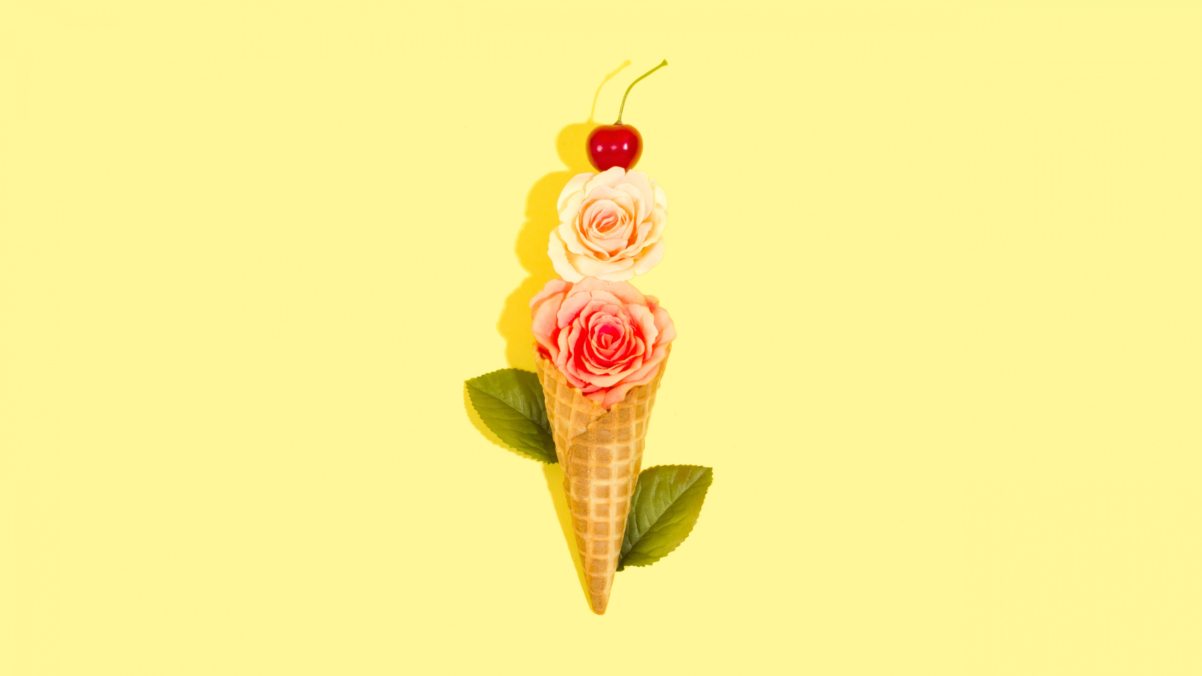 An ice cream cone decorated with rose flowers, cherries, and green leaves on a bright yellow background.
