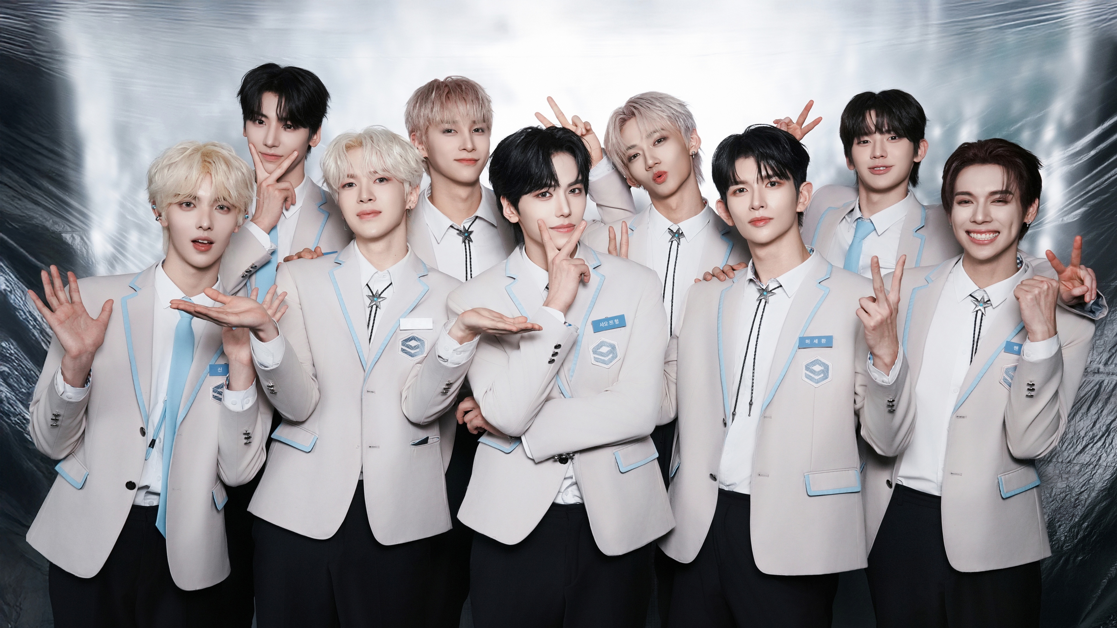 A group of stylish South Korean K-pop singers posing together in a professional studio setting.