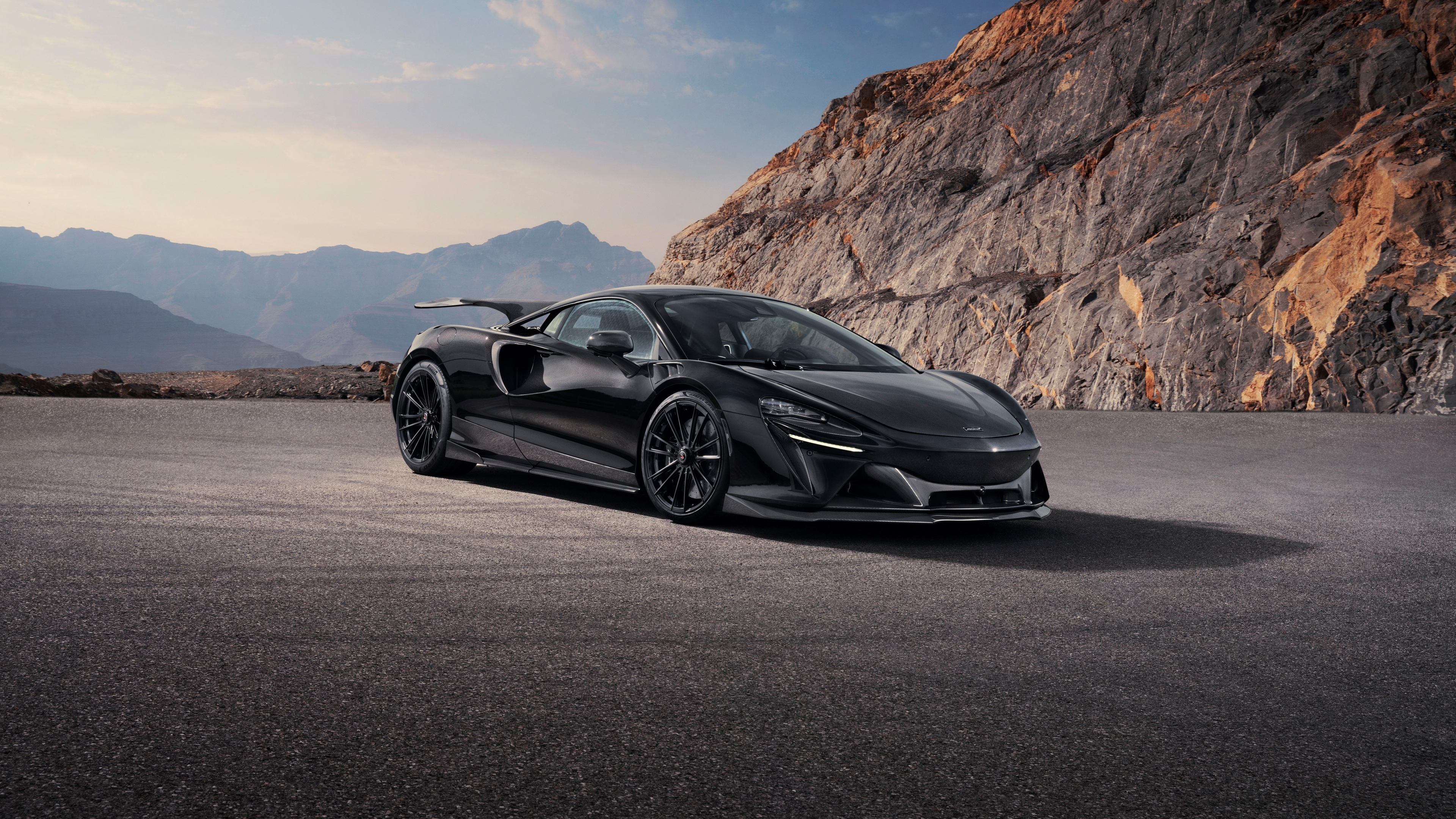 A high-detail shot of a 2024 McLaren Artura modified by Novitec, showcasing prominent carbon fiber body parts and aerodynamic styling.