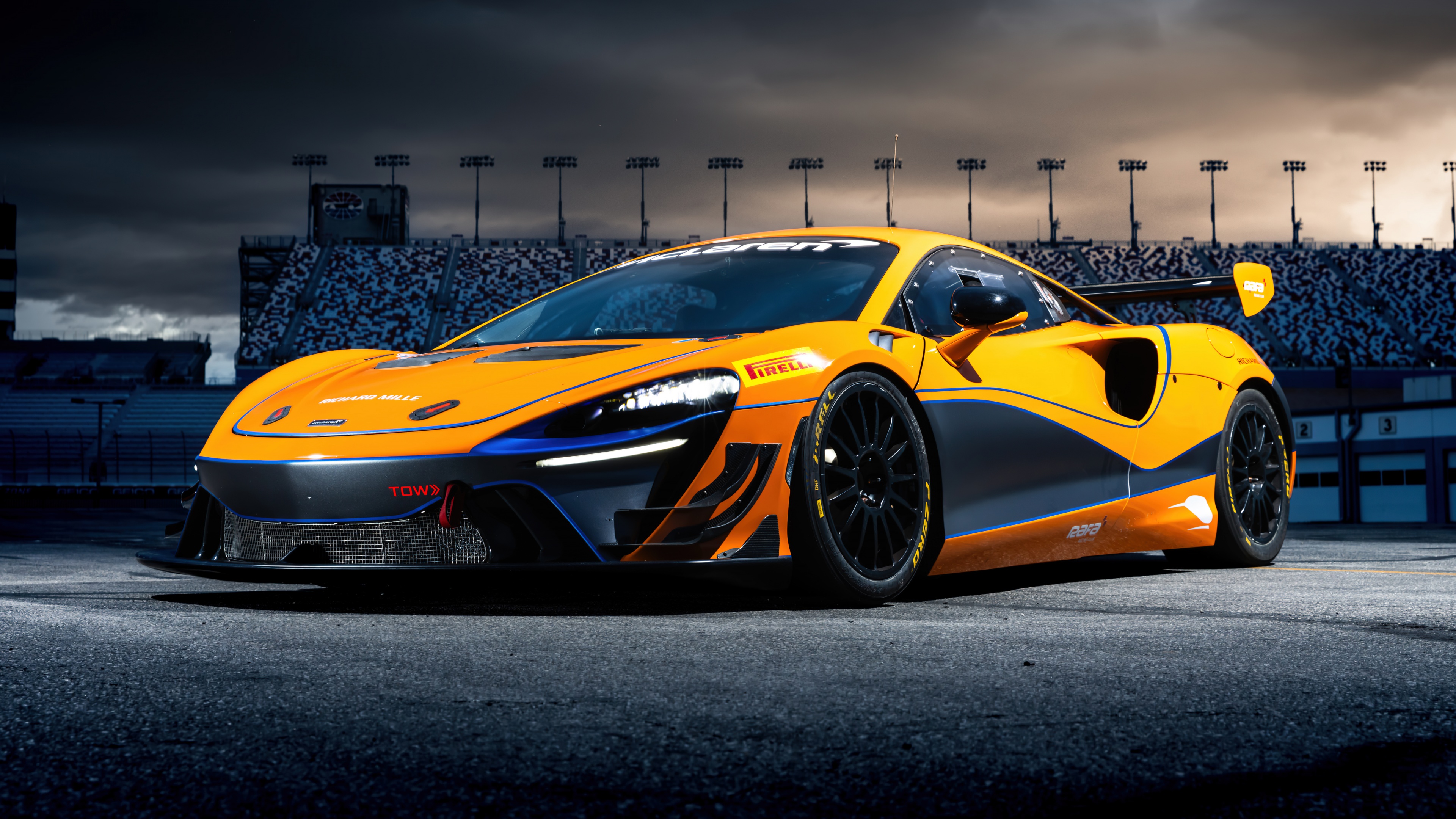 A McLaren Artura GT4 race car driving fast on a professional asphalt race track.