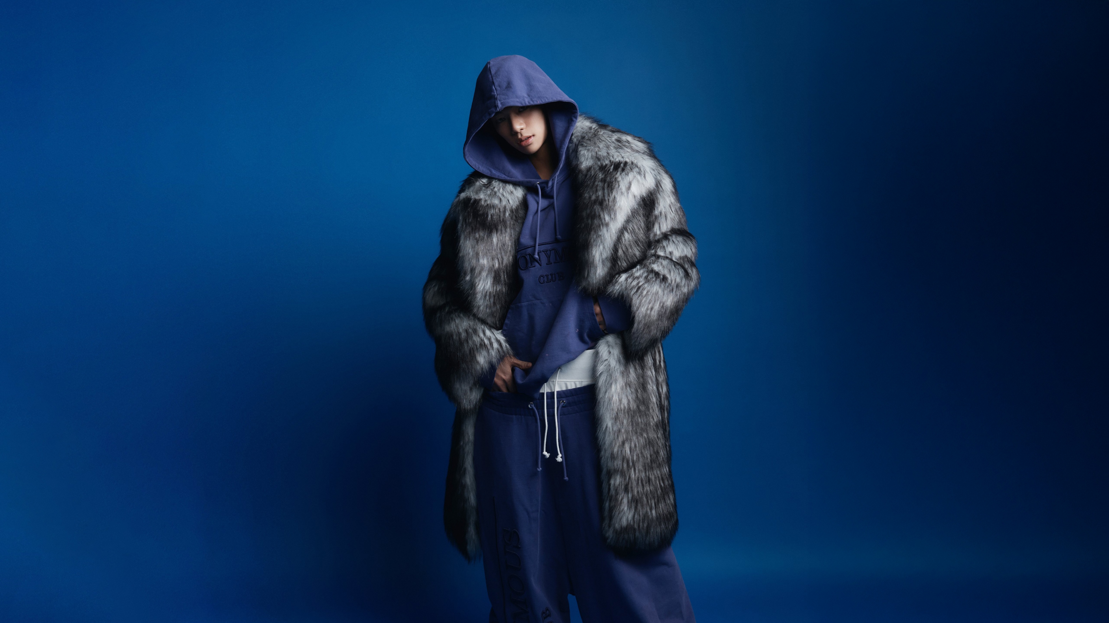 A high-resolution, detailed portrait of South Korean rapper Tarzzan from ALLDAY PROJECT set against a vibrant blue background.