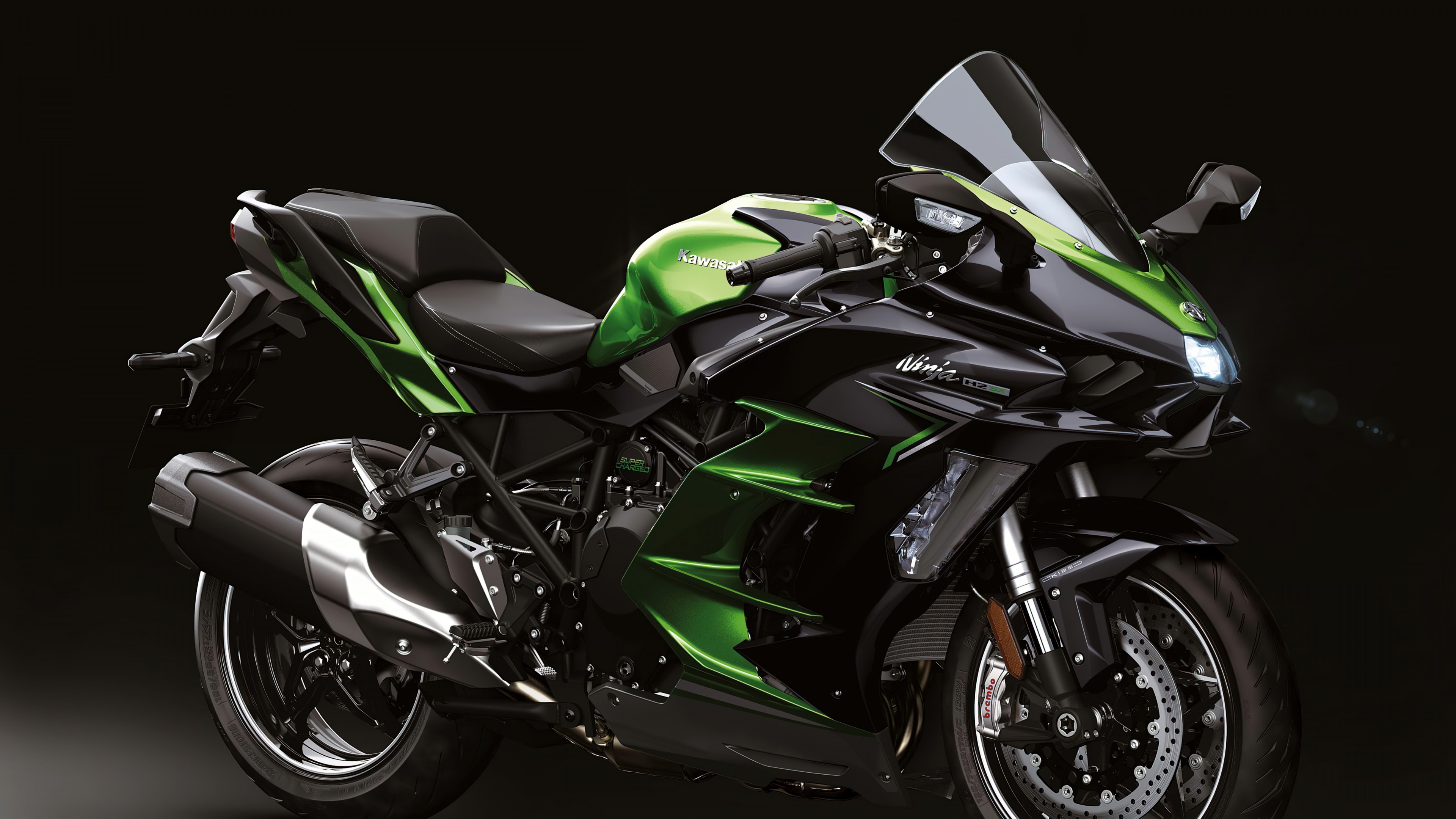Close-up professional shot of a black Kawasaki Ninja H2 SX sports motorcycle against a dark background.