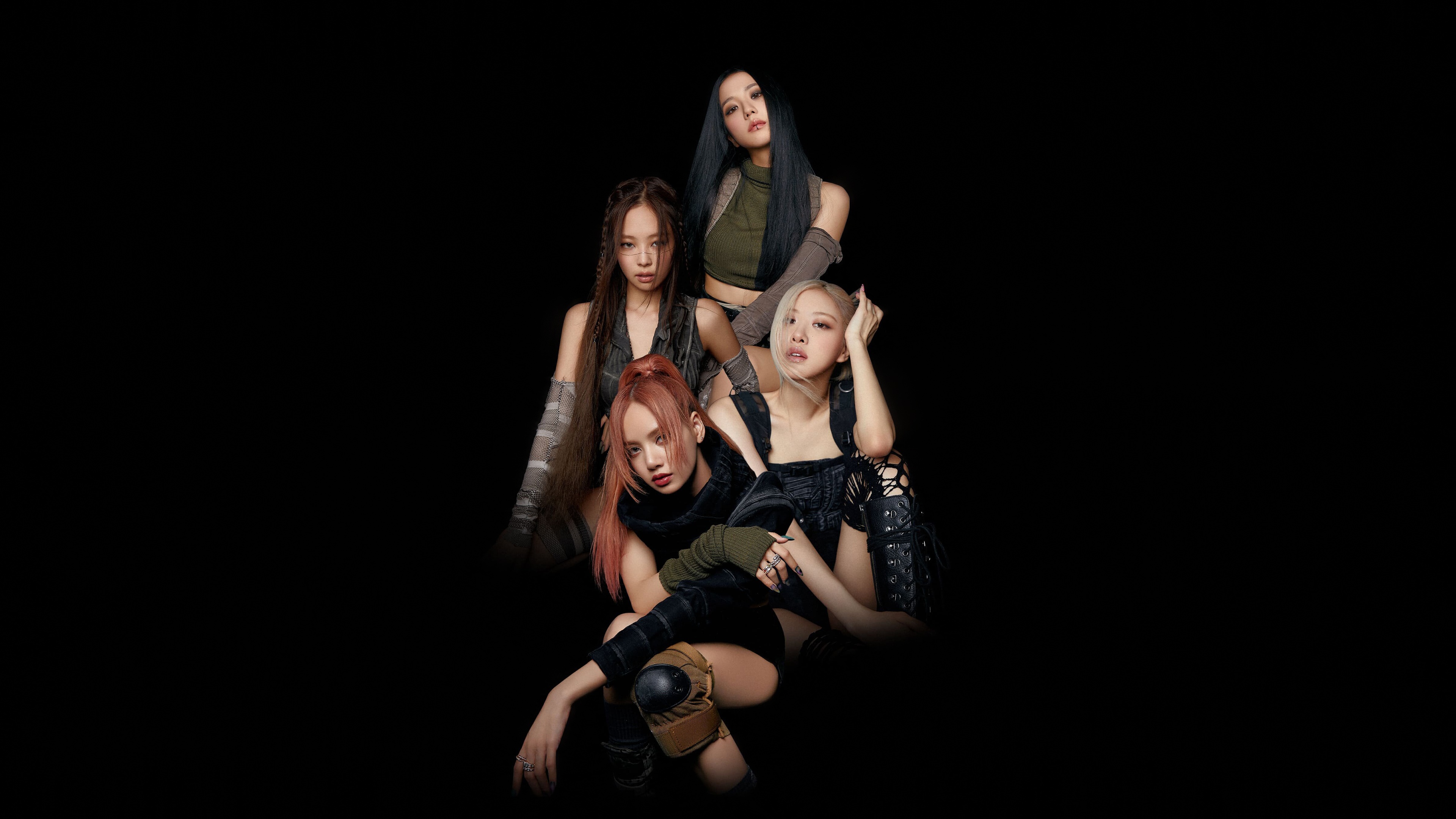 A group portrait of Blackpink members Lisa, Jennie, Jisoo, and Rosé against a solid black background.
