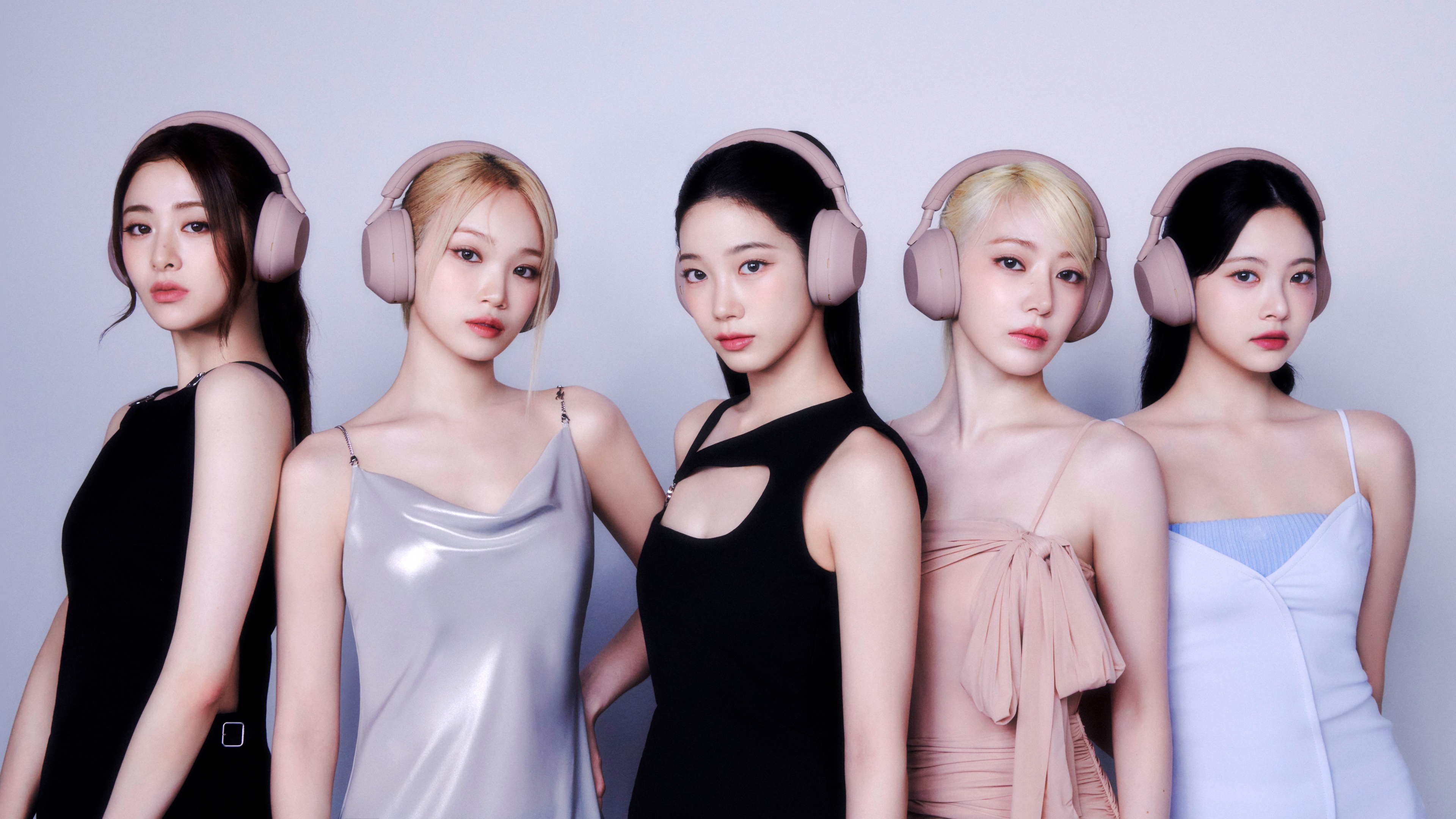 The members of LE SSERAFIM—Sakura, Chaewon, Yunjin, Eunchae, and Kazuha—wearing headphones in a high-definition close-up.