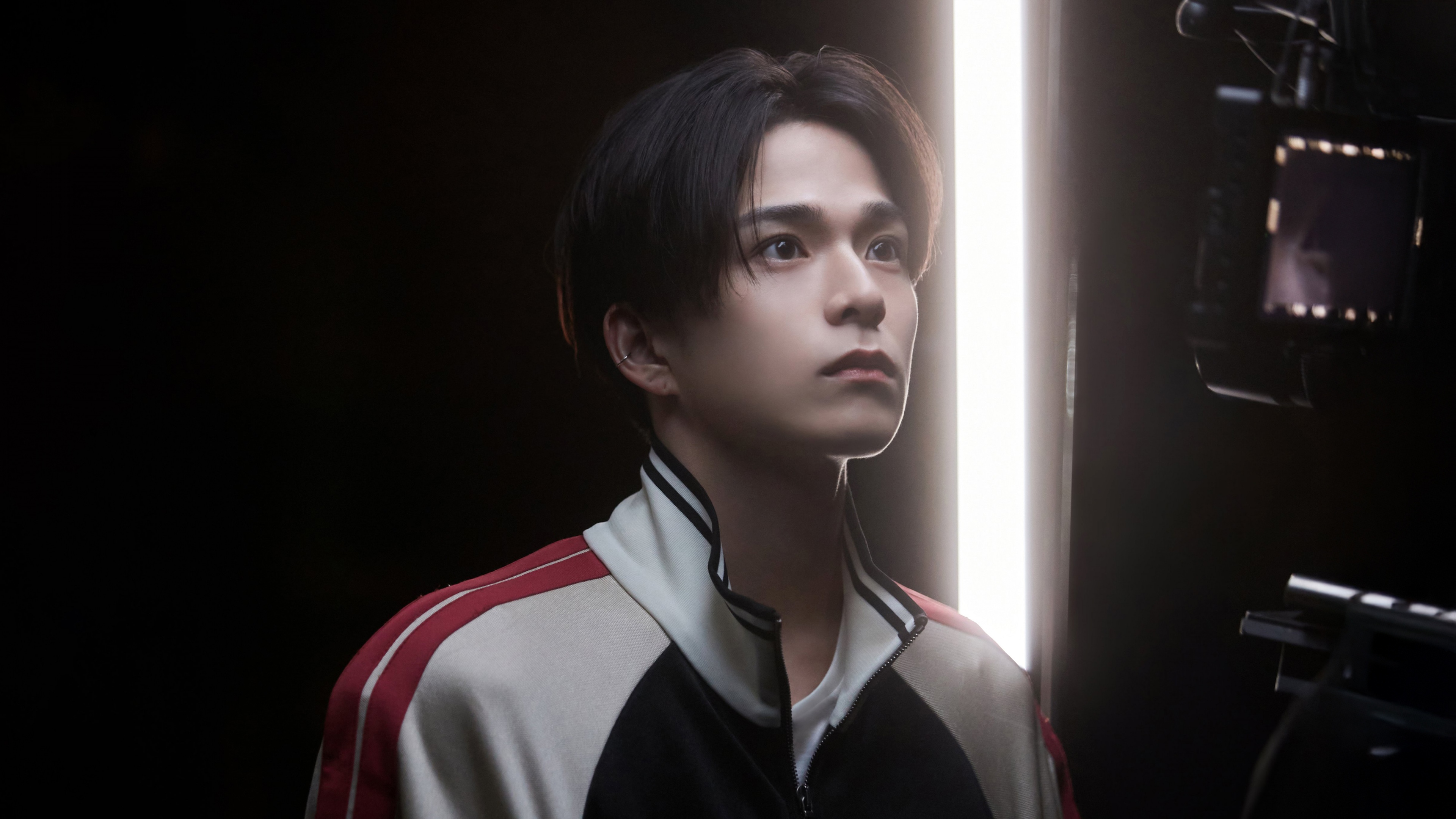 A group of charismatic K-Pop boy band members posing against a dark, atmospheric background with dramatic studio lighting.
