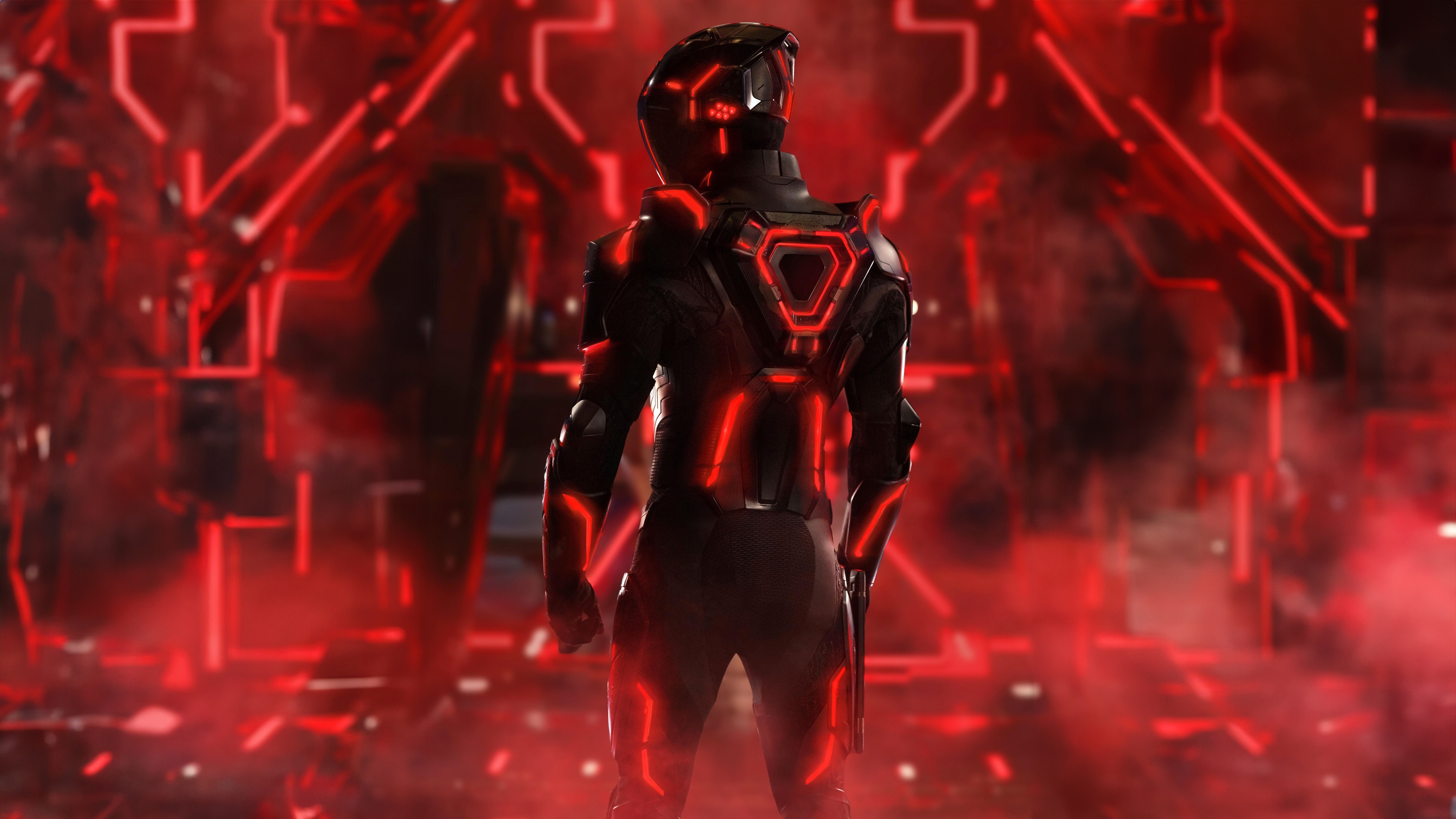 A character from Tron: Ares wearing glowing red futuristic cybernetic armor in a dark digital environment.