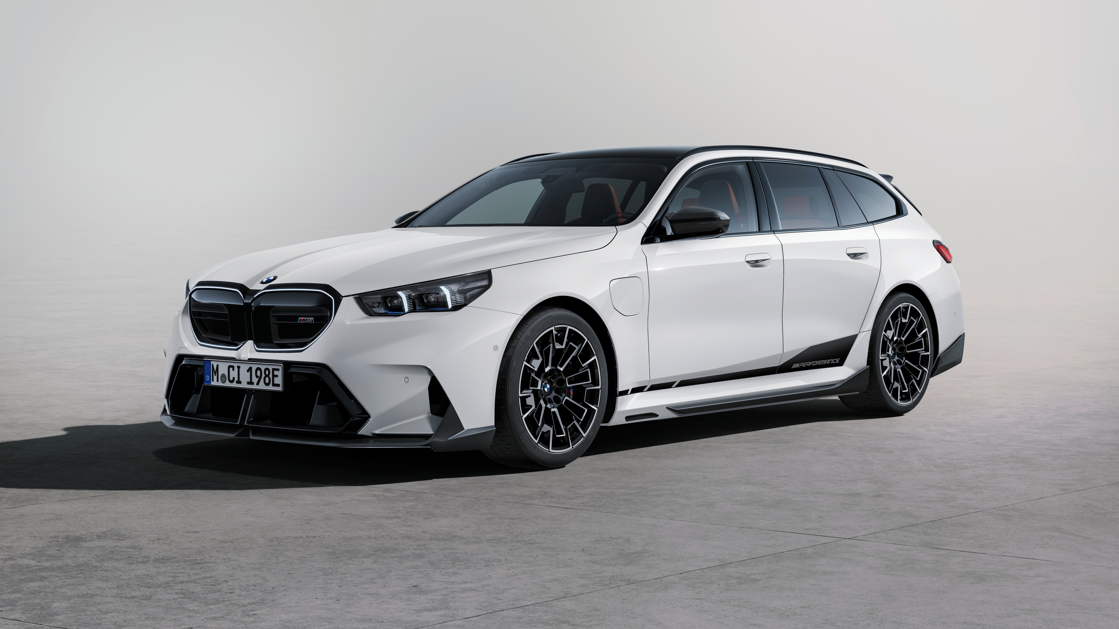 A white 2024 BMW M5 featuring aerodynamic M Performance Parts and a sporty design.