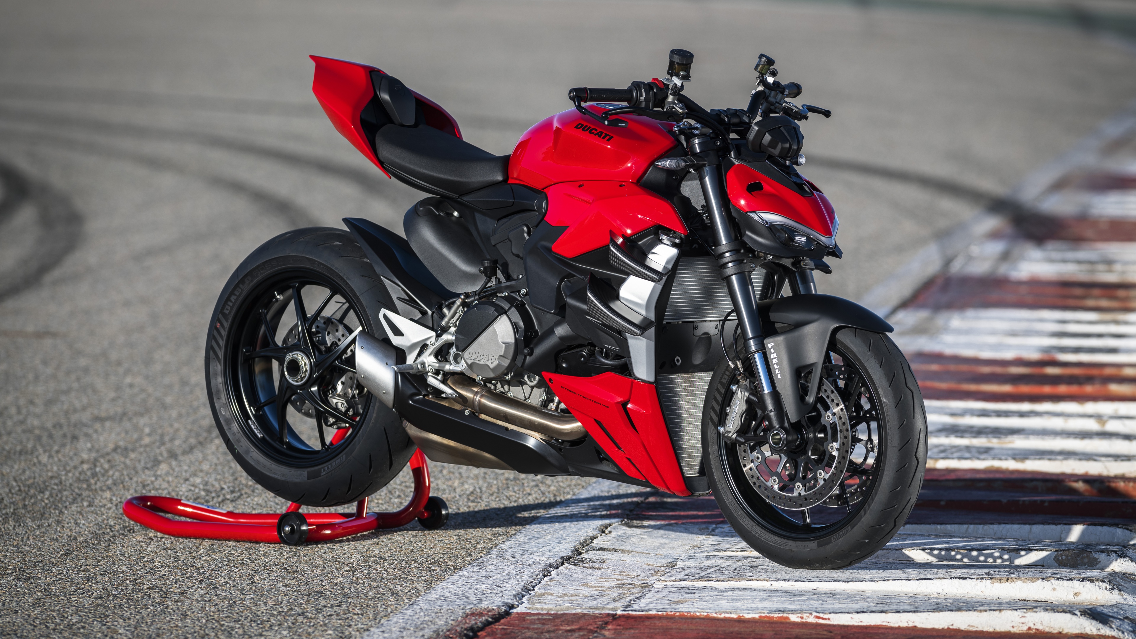 A high-resolution, close-up shot of a red and black Ducati Streetfighter V2 motorcycle, highlighting its muscular frame and sharp, modern design.
