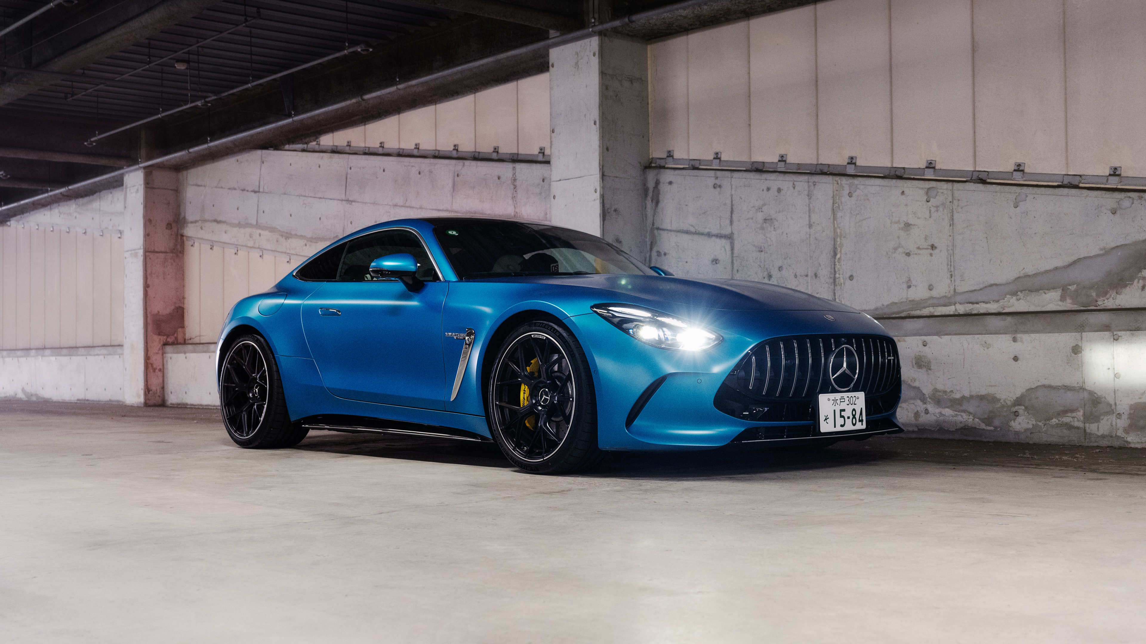 A detailed view of the 2024 Mercedes-AMG GT 63 4MATIC+ highlighting its sleek metallic finish and aggressive front-end design.