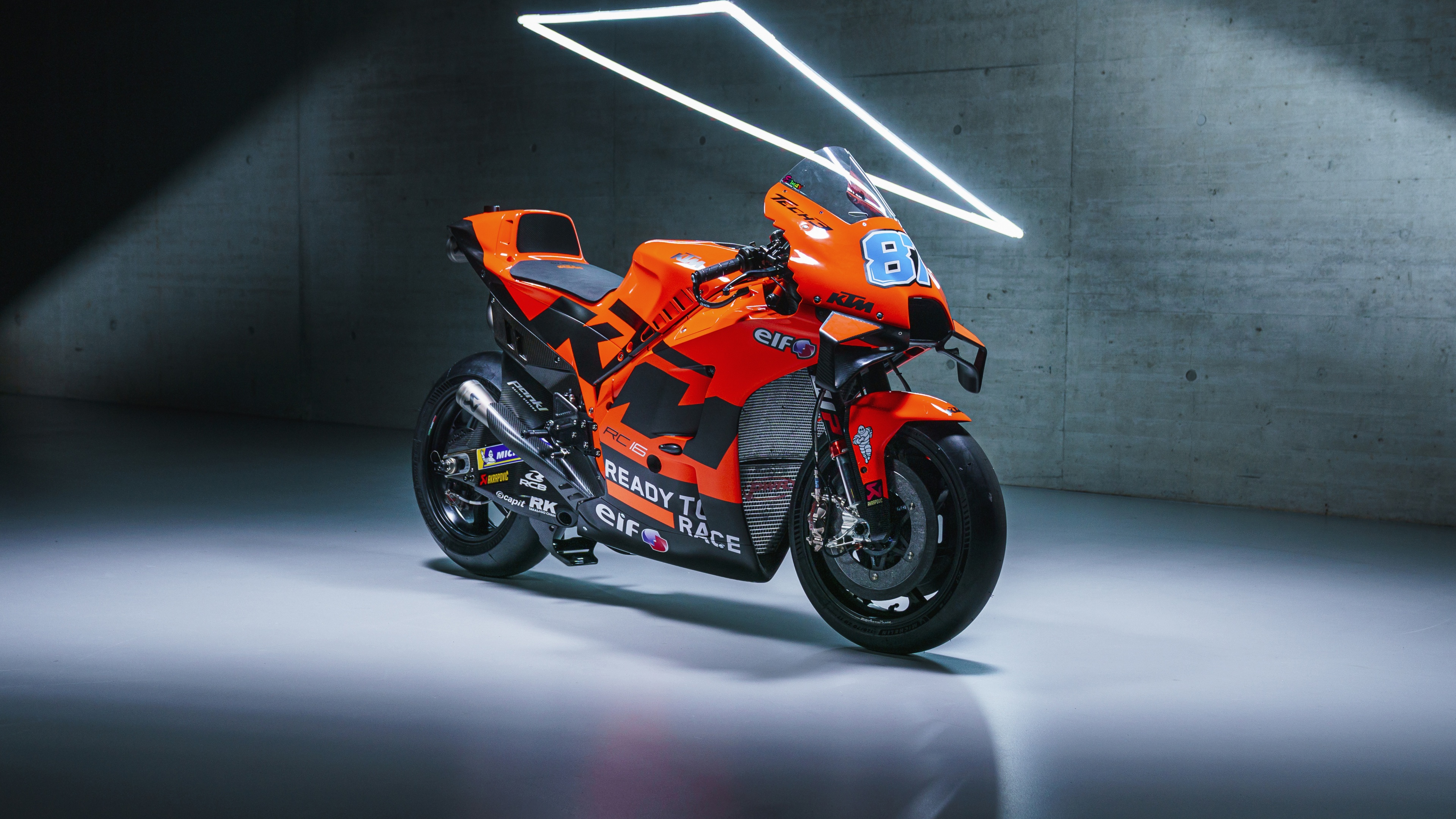 Professional MotoGP racing motorcycles maneuvering through a corner on a racetrack during the 2022 season.