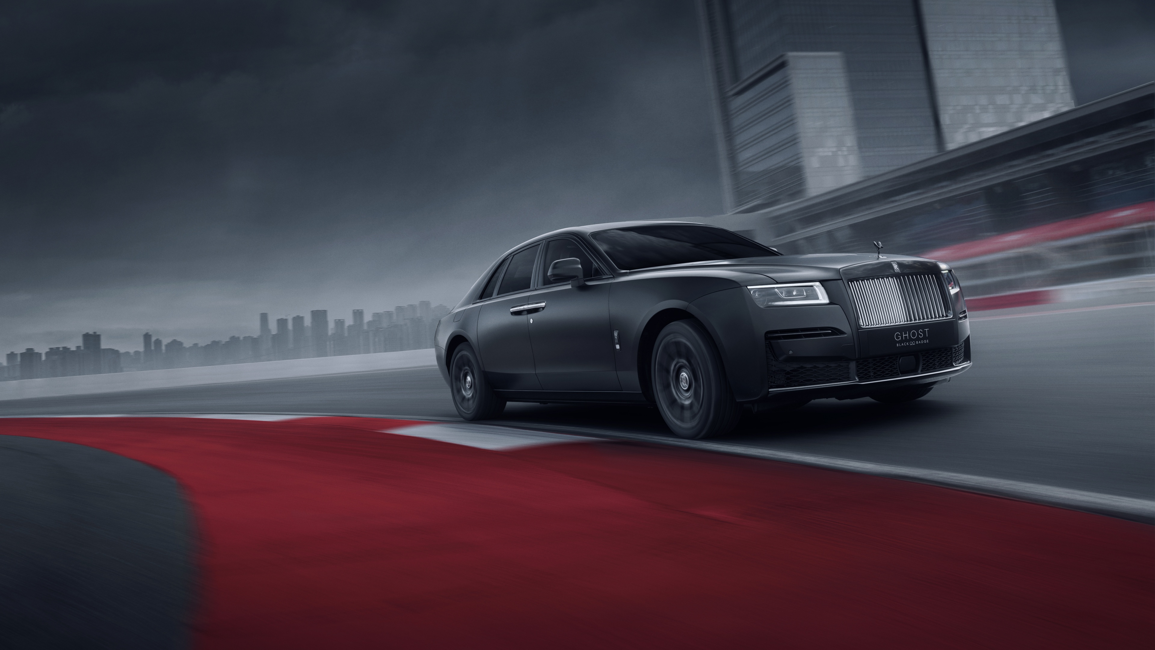 A sleek black Rolls-Royce Black Badge Ghost driving on a smooth race track.