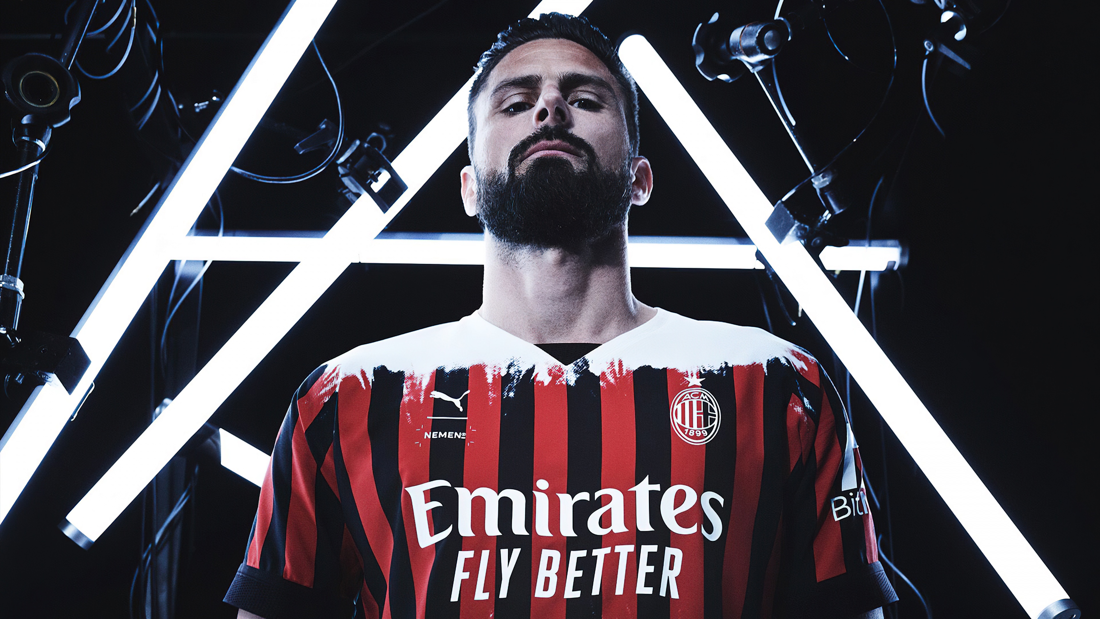 A professional soccer player wearing the classic AC Milan red and black striped jersey.