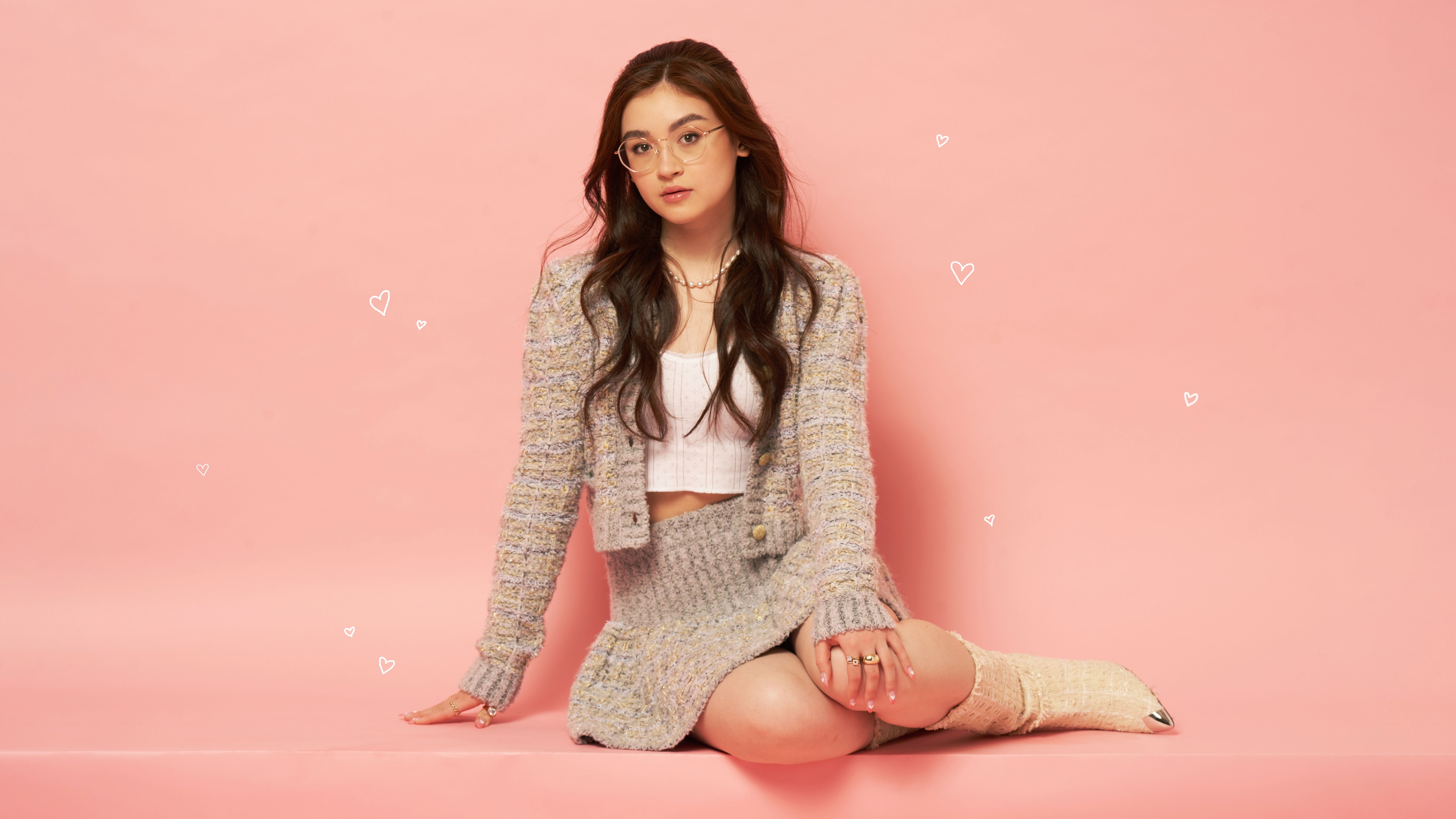 A professional close-up portrait of actress Anna Cathcart against a solid peach background.