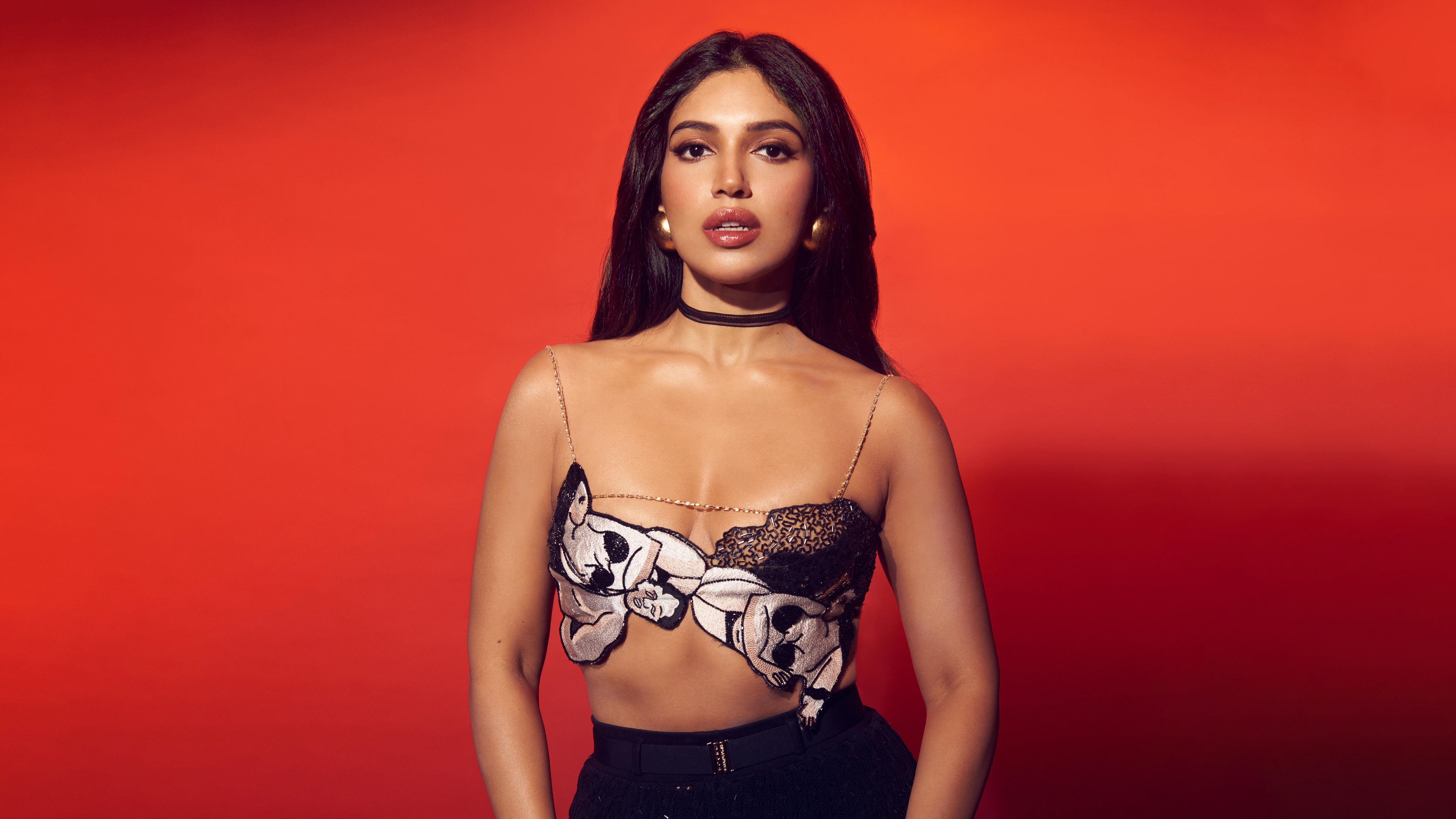 A stunning portrait of Indian actress Bhumi Pednekar against a bright orange backdrop.