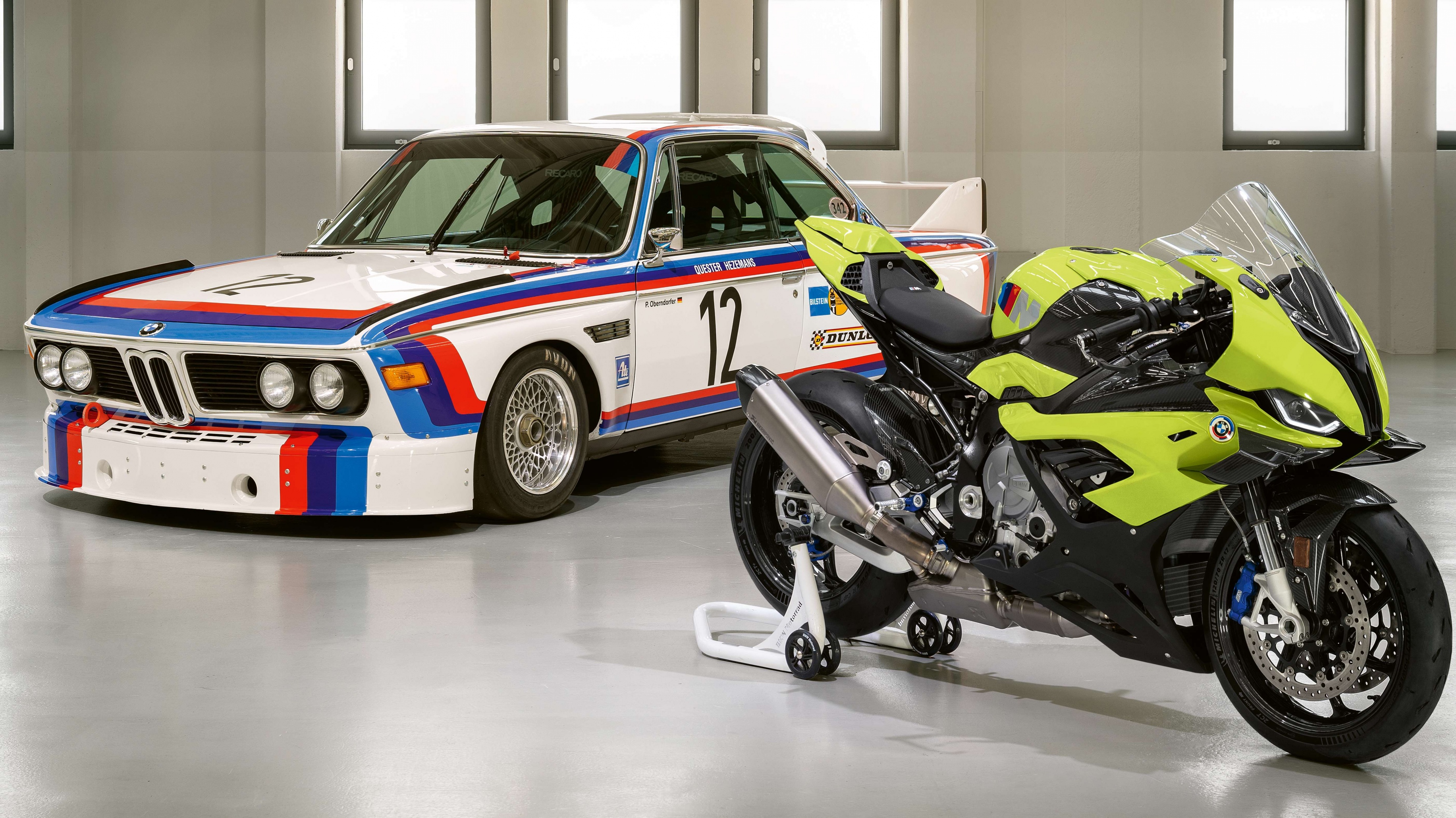 A side-by-side display of the BMW M 1000 RR superbike and the classic BMW 3.0 CSL celebrating a 50th anniversary special edition.