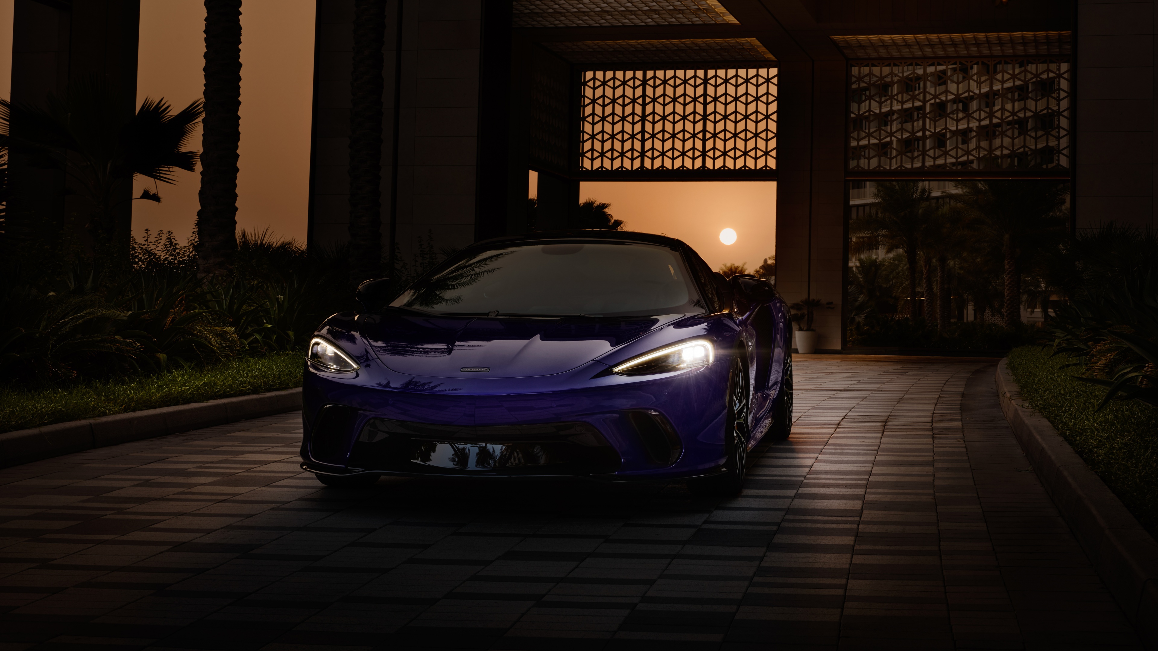 A high-detail night shot of a 2024 McLaren GTS supercar with urban light reflections on its polished body.