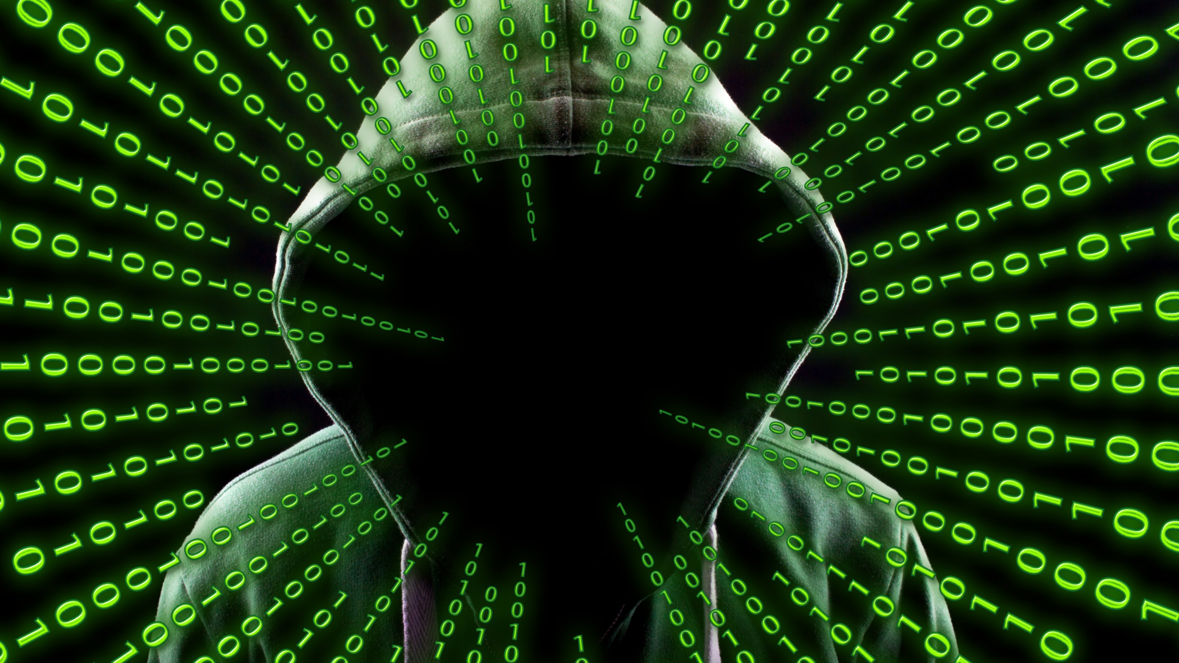 A person wearing a dark hoodie surrounded by falling green binary digits and matrix-style digital code.