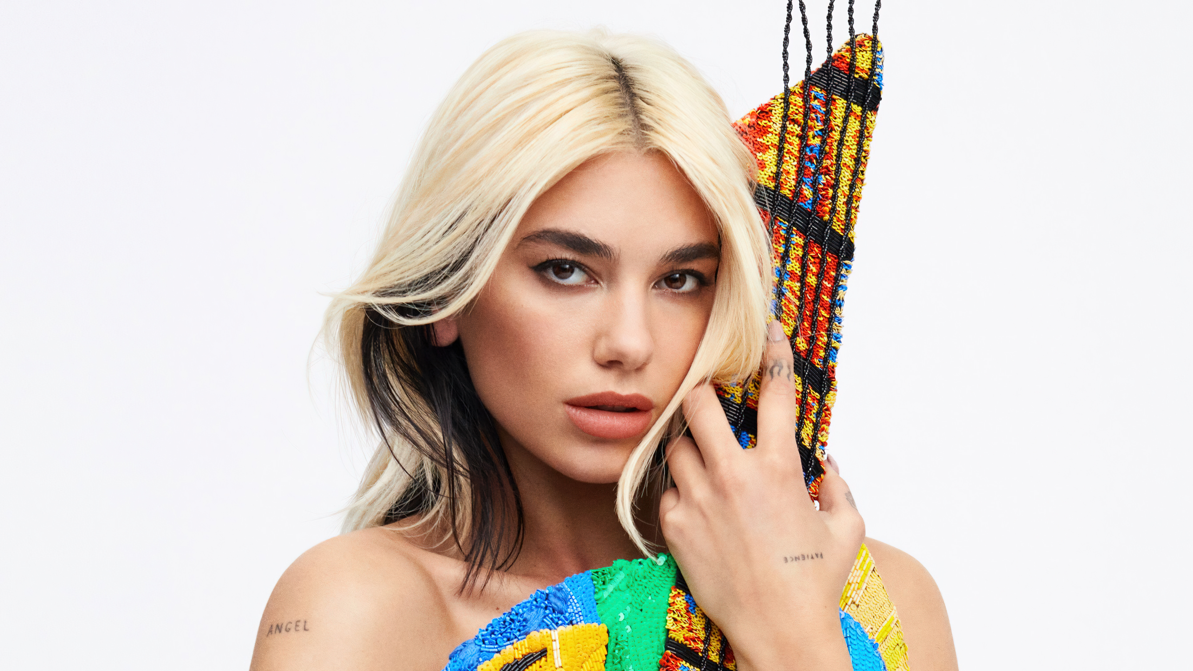 A professional studio portrait of Dua Lipa for an Elle Magazine cover shot on a seamless white background.